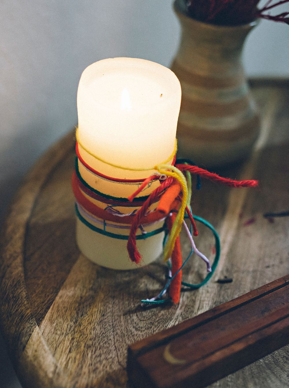 Decorative glass jars with colorful string tied around their necks arranged in a row on a rustic wooden surface.