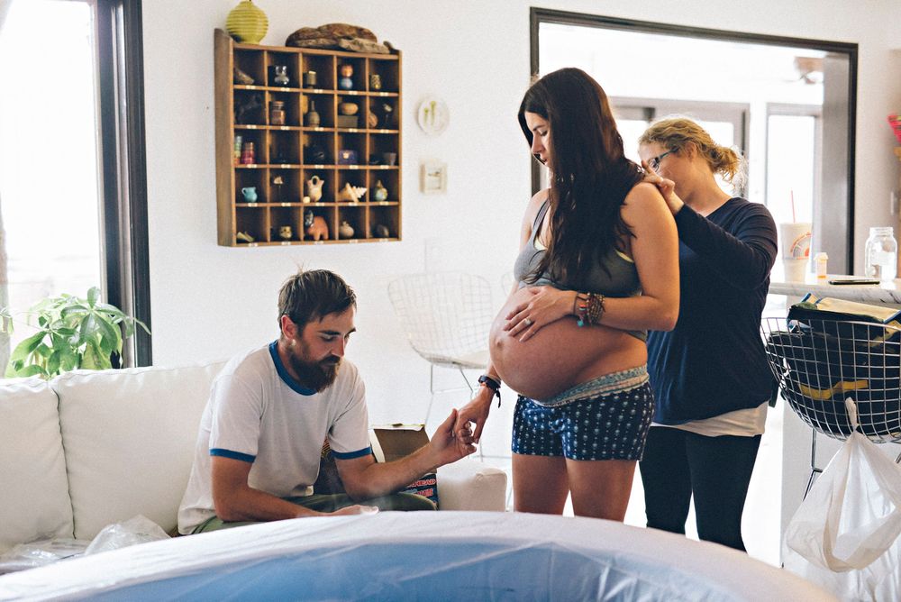 Medical professionals examine and prepare for a home birth with an expectant mother in a bright living room setting.
