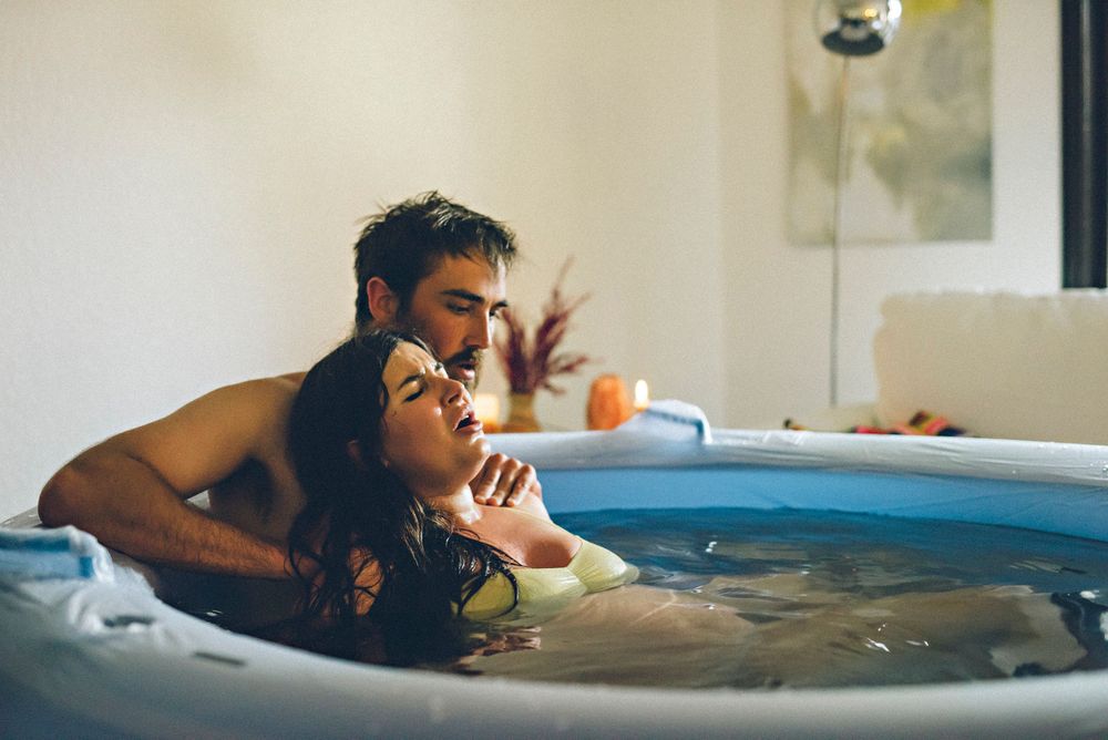 Person relaxing in a wooden hot tub while enjoying a refreshing beverage in an outdoor setting.