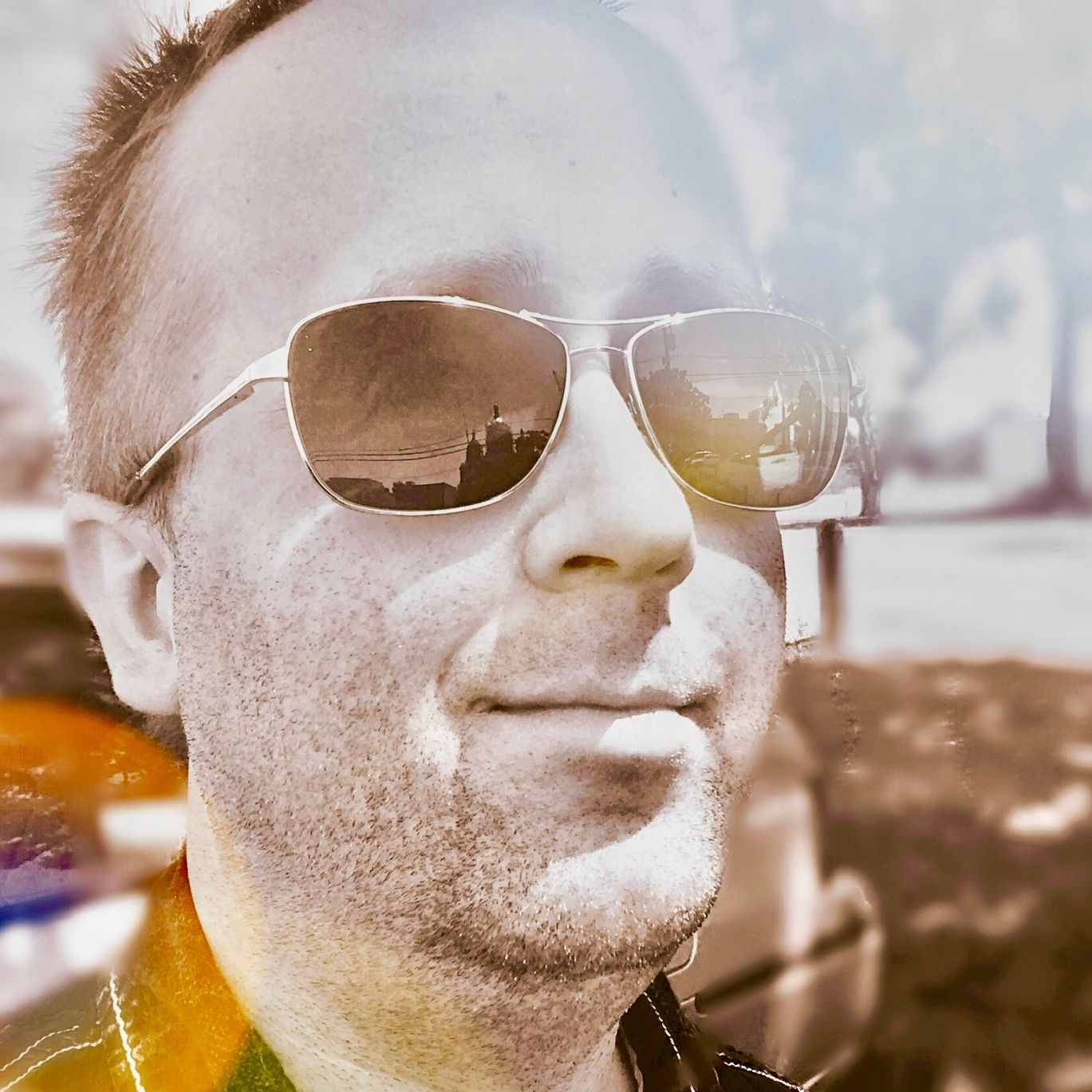 Close-up selfie with sunglasses reflecting scenic view at sunset.