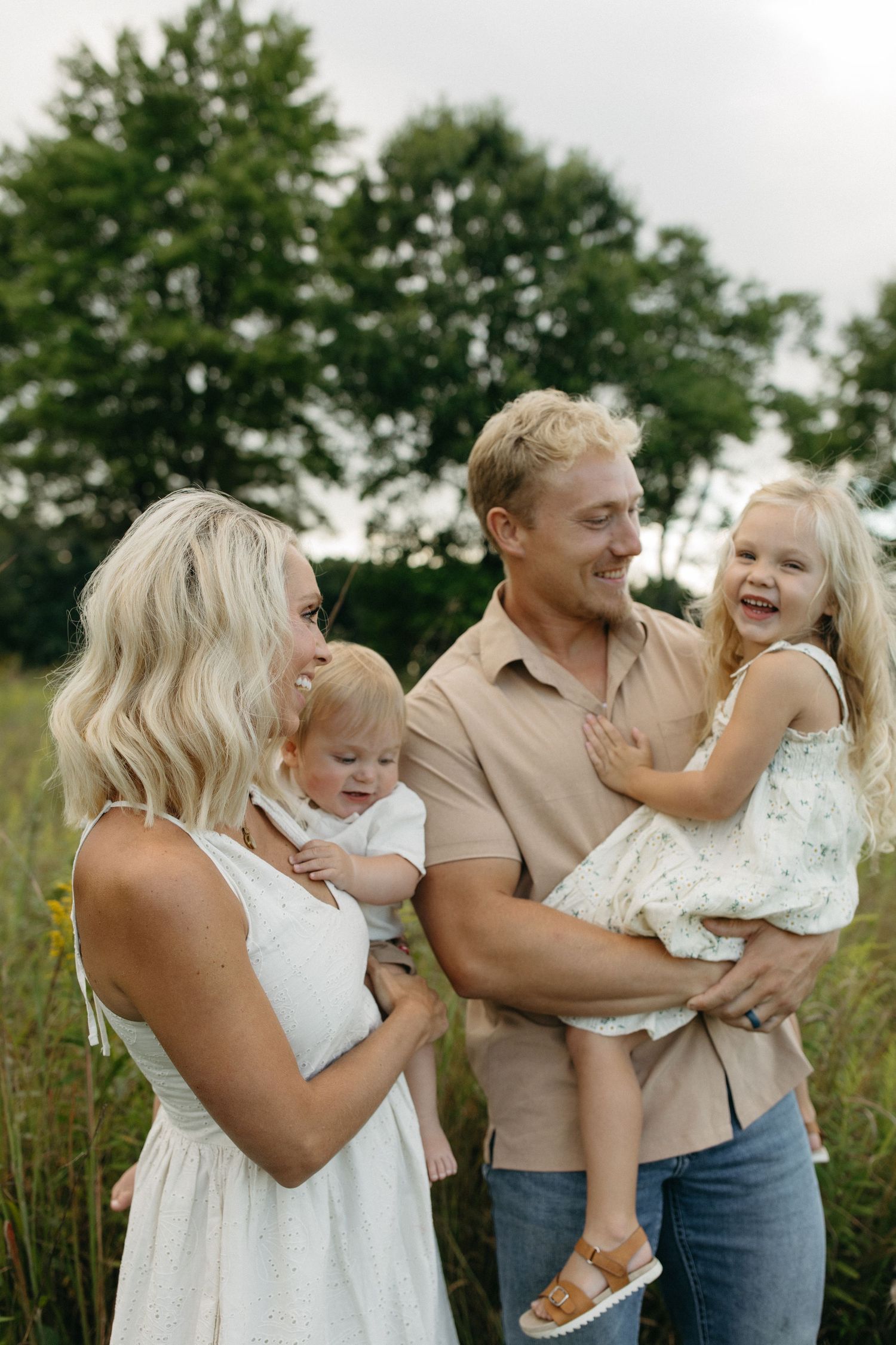 Parents smiling and hoiding their children during a relaxed lifestyle photo session in a field