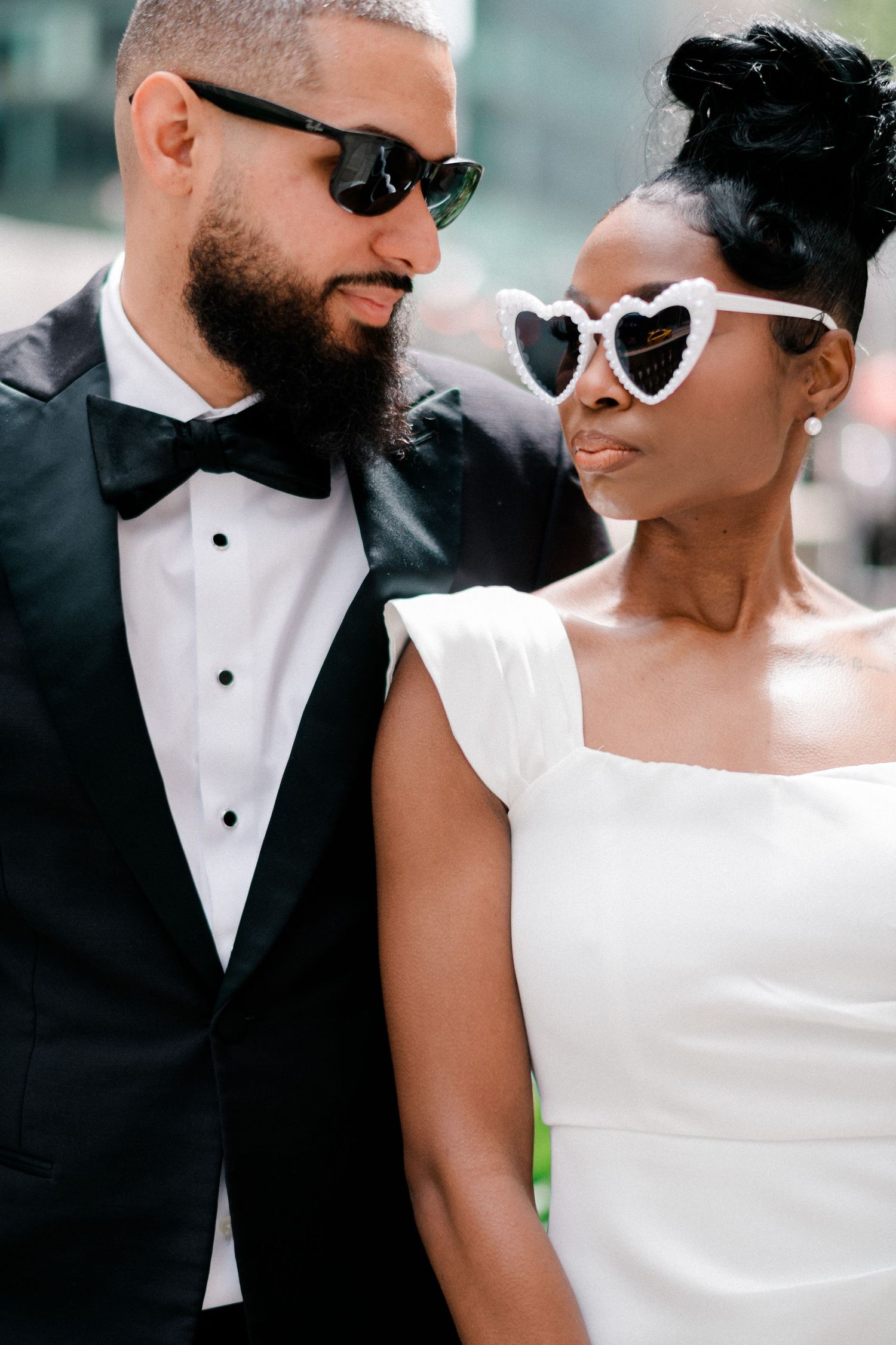 A close-up portrait shows a romantic couple wearing white and black formal attire with sunglasses. Gricel's Photography NYC Engagement NYPL