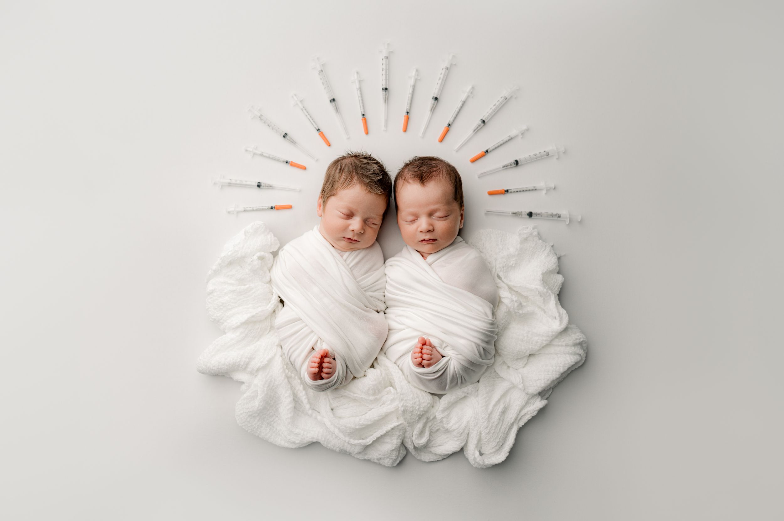 Twins laying on a bed posing for Jacksonville baby photographer, Ashley Wilson