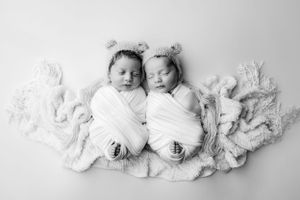Newborn twin infants laying on a bed in Jacksonville baby studio