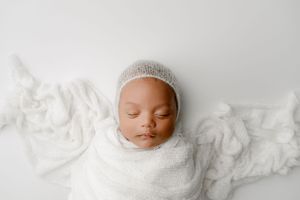 Infant wrapped in white sleeping for photography session in a studio