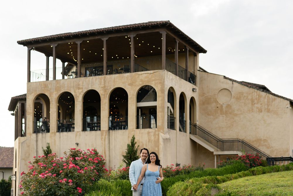 Mediterranean style mansion with arched windows and elegant stone facade sits atop a green hillside.
