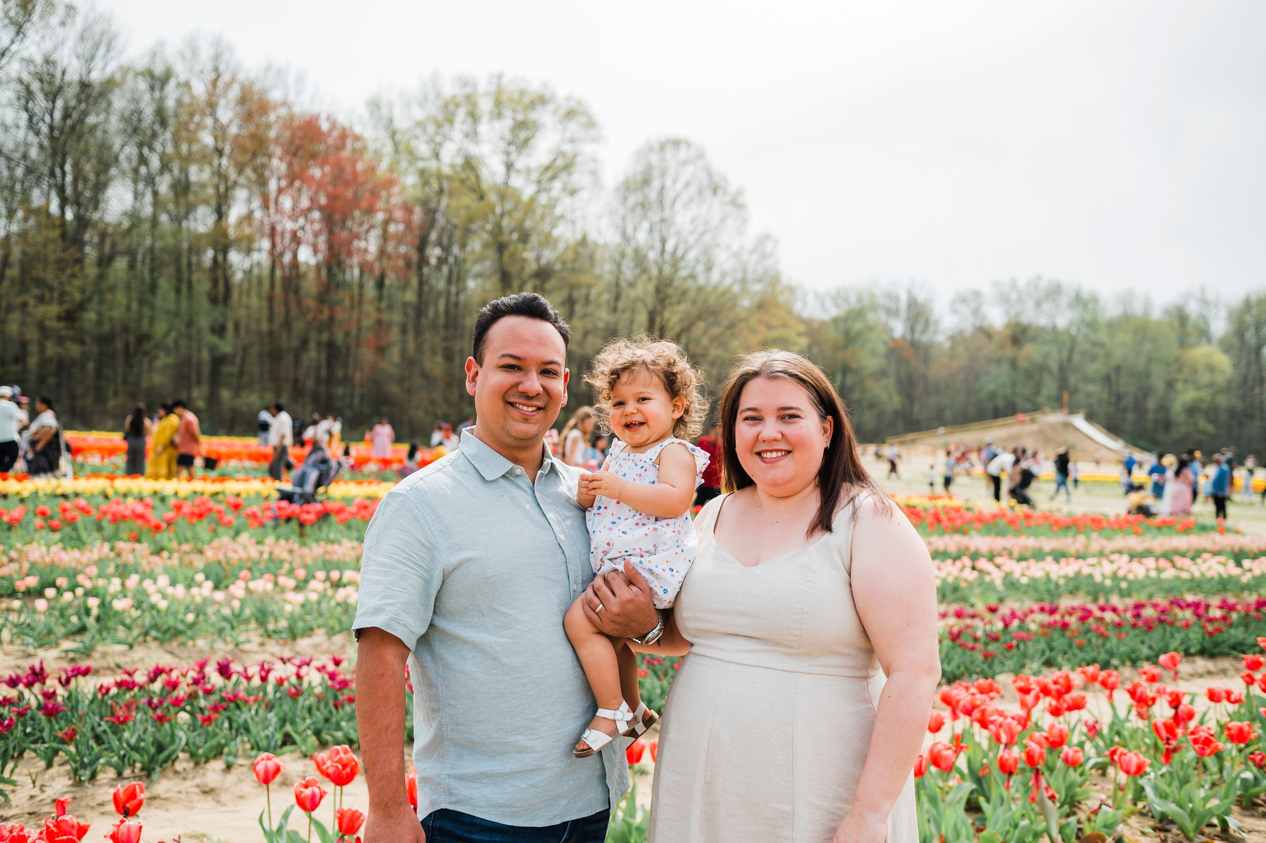 Family enjoying a spring day together at a vibrant tulip garden with colorful flowers blooming in the background.
