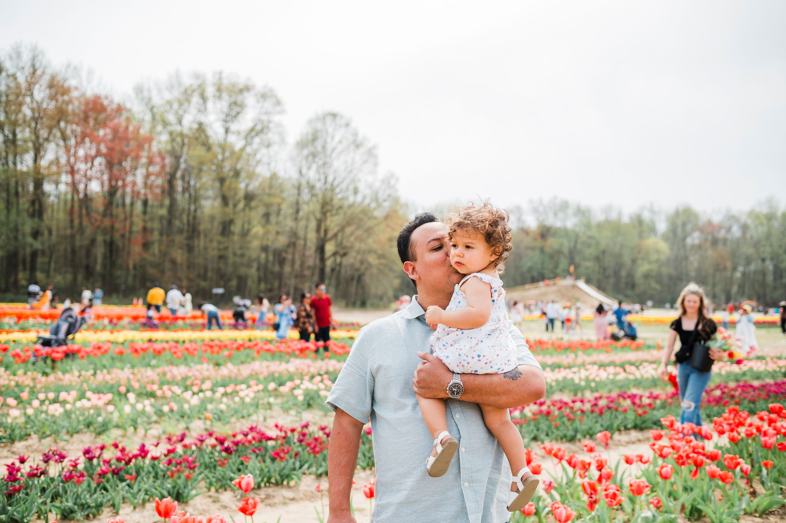 Candid moment captured in a tulip field with red and pink flowers creating a stunning natural backdrop.