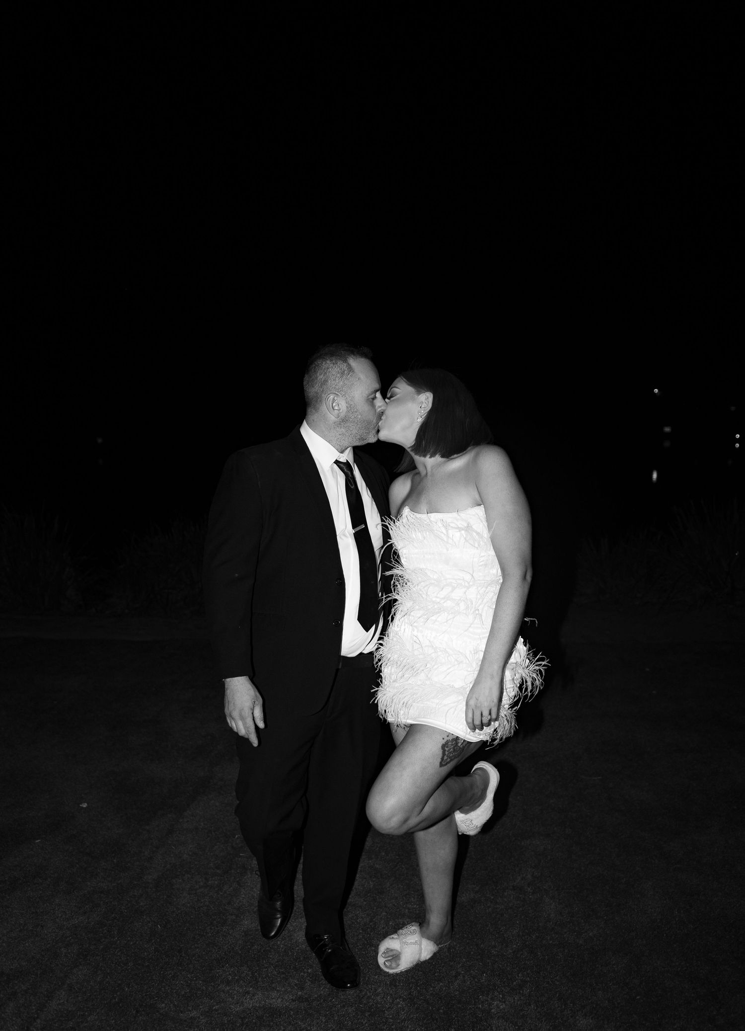 Dramatic night wedding photos showing couple dancing in dark outdoor setting.