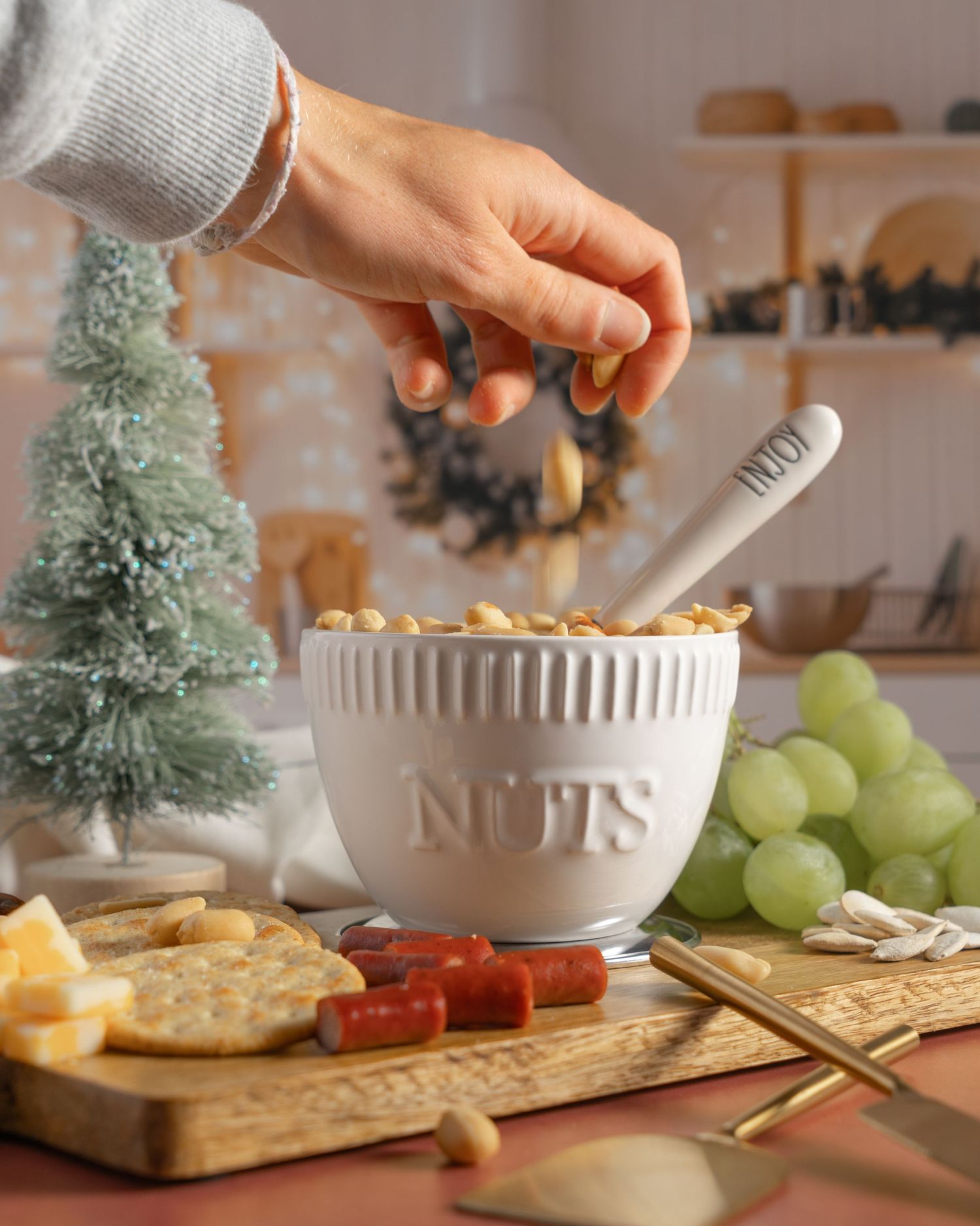 nut and cheese platter with Christmas tree in background