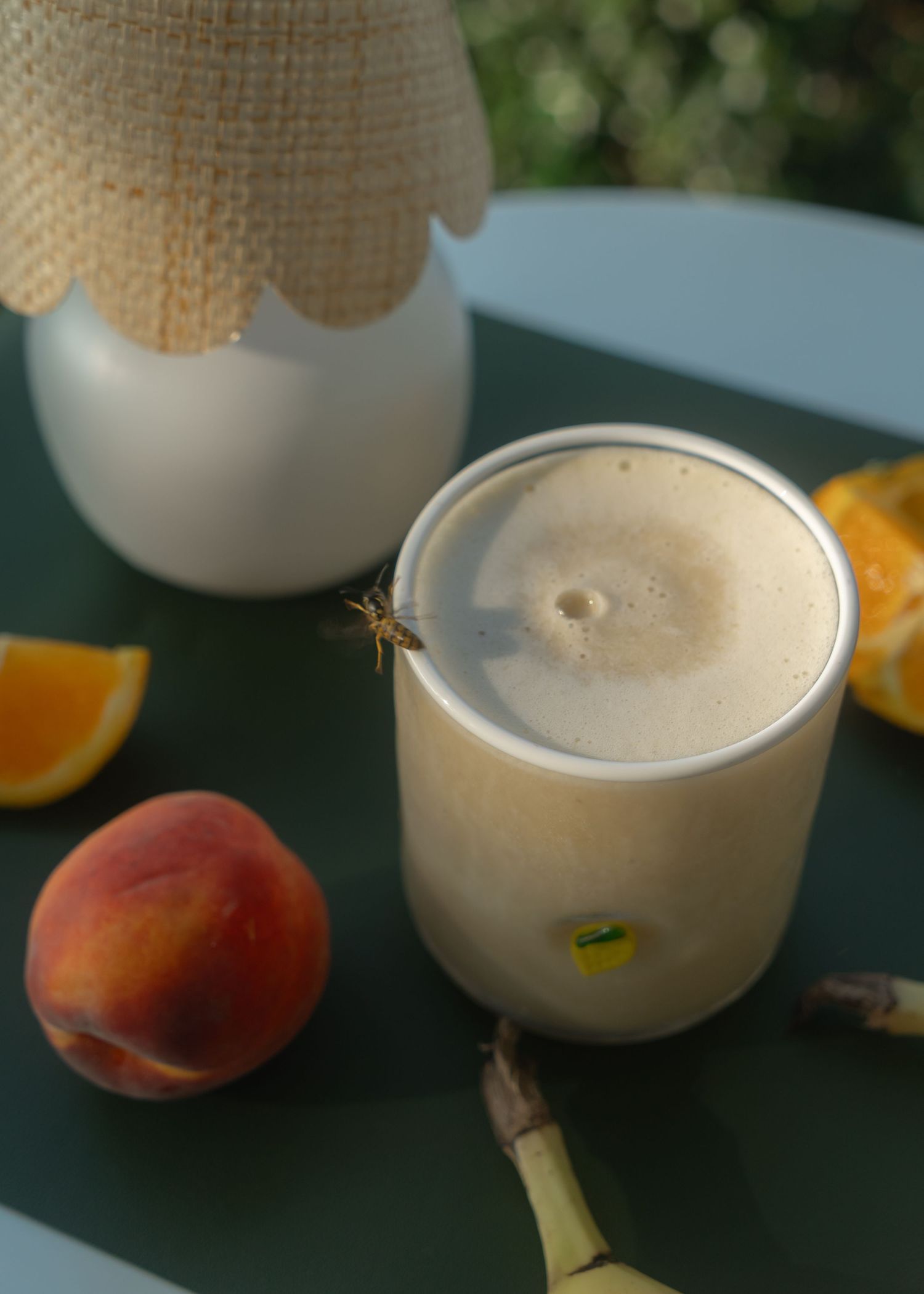 Bee flying around orange protein shake in clear glass