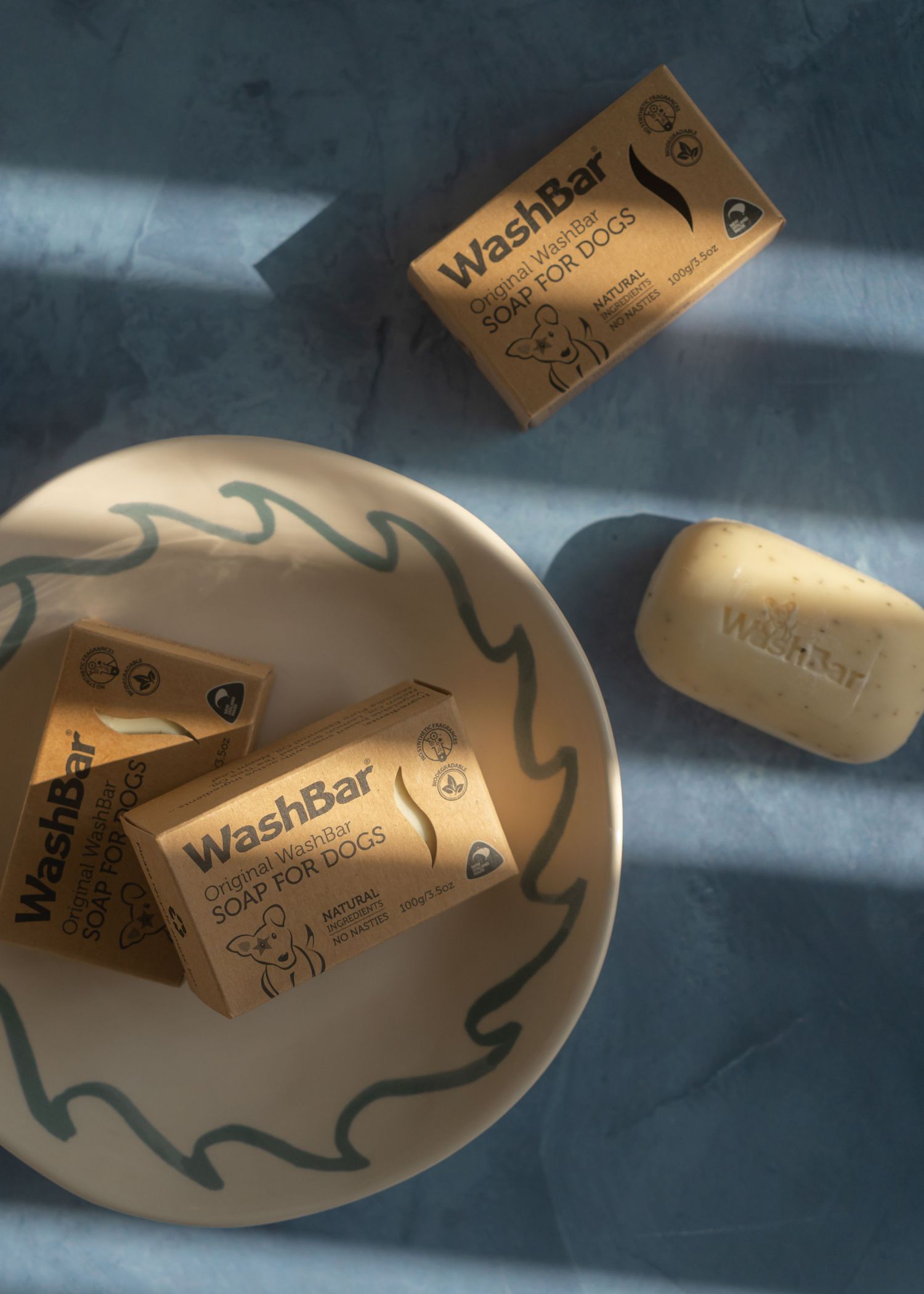 Three WashBar soaps laying on blue surface