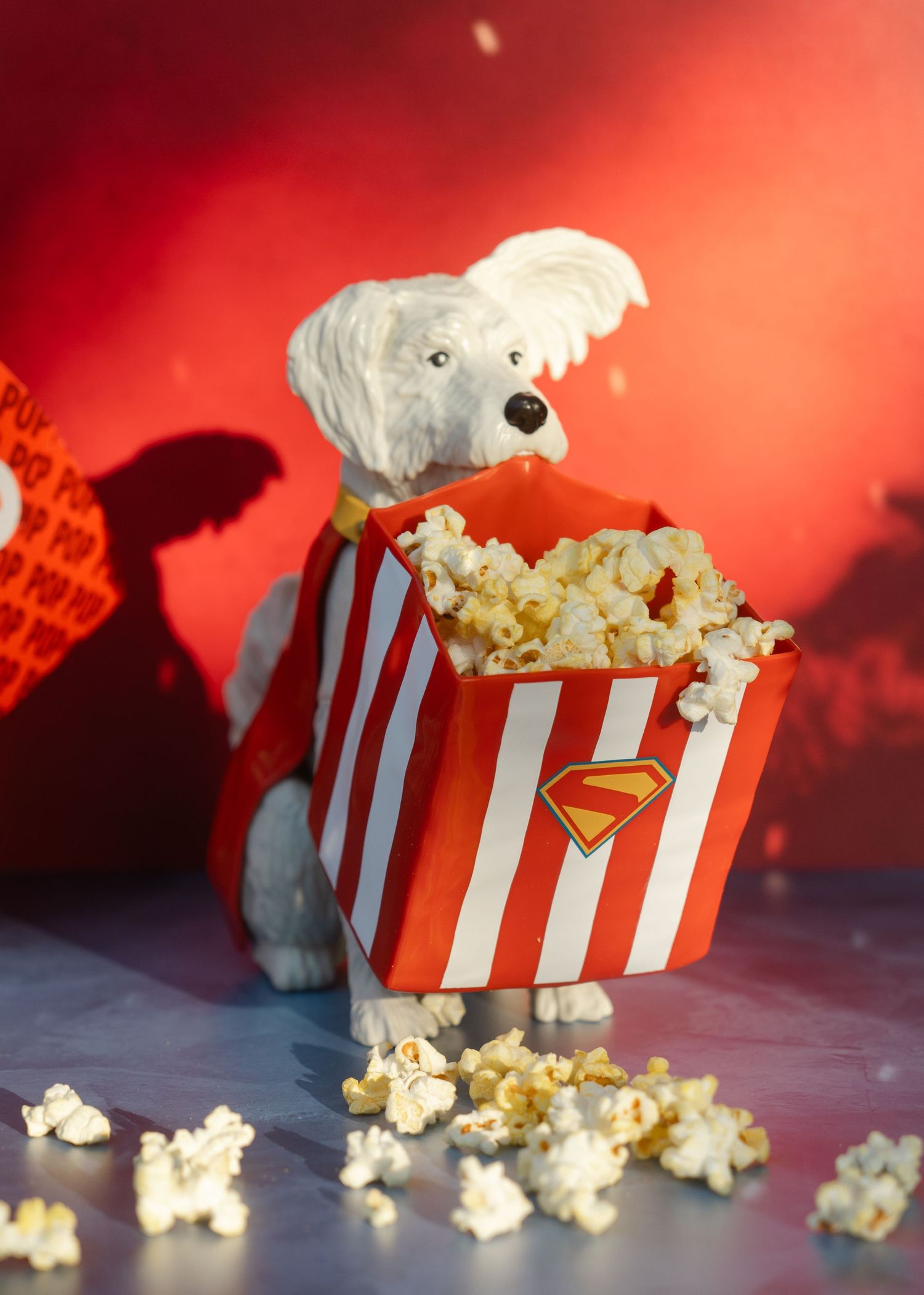 suer dog popcorn bucket on blue surface with popcorn on the foreground