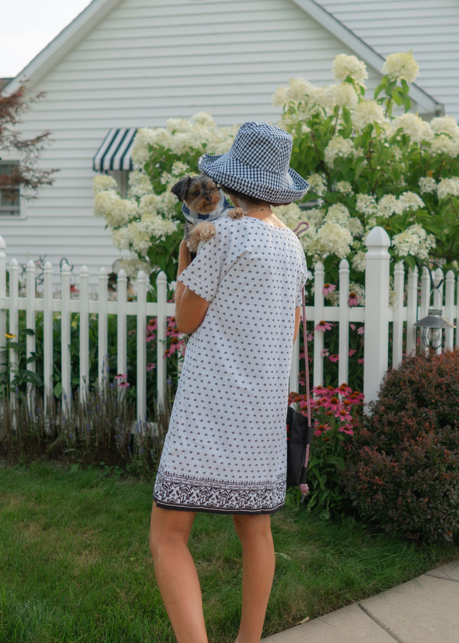 female in blue and white dress holding a dog