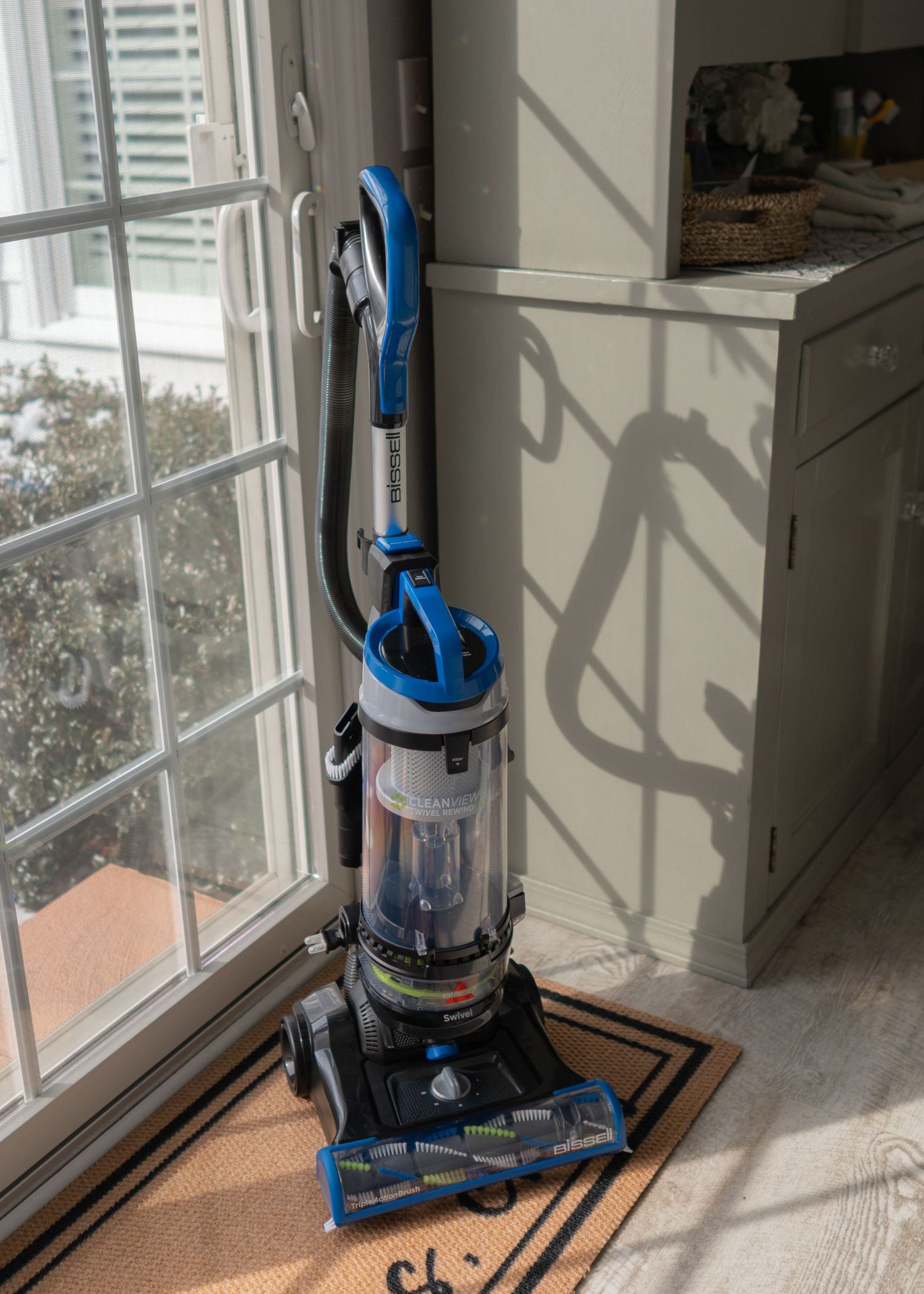 Bissel Sweeper sitting on a floor mat by the sliding glass door