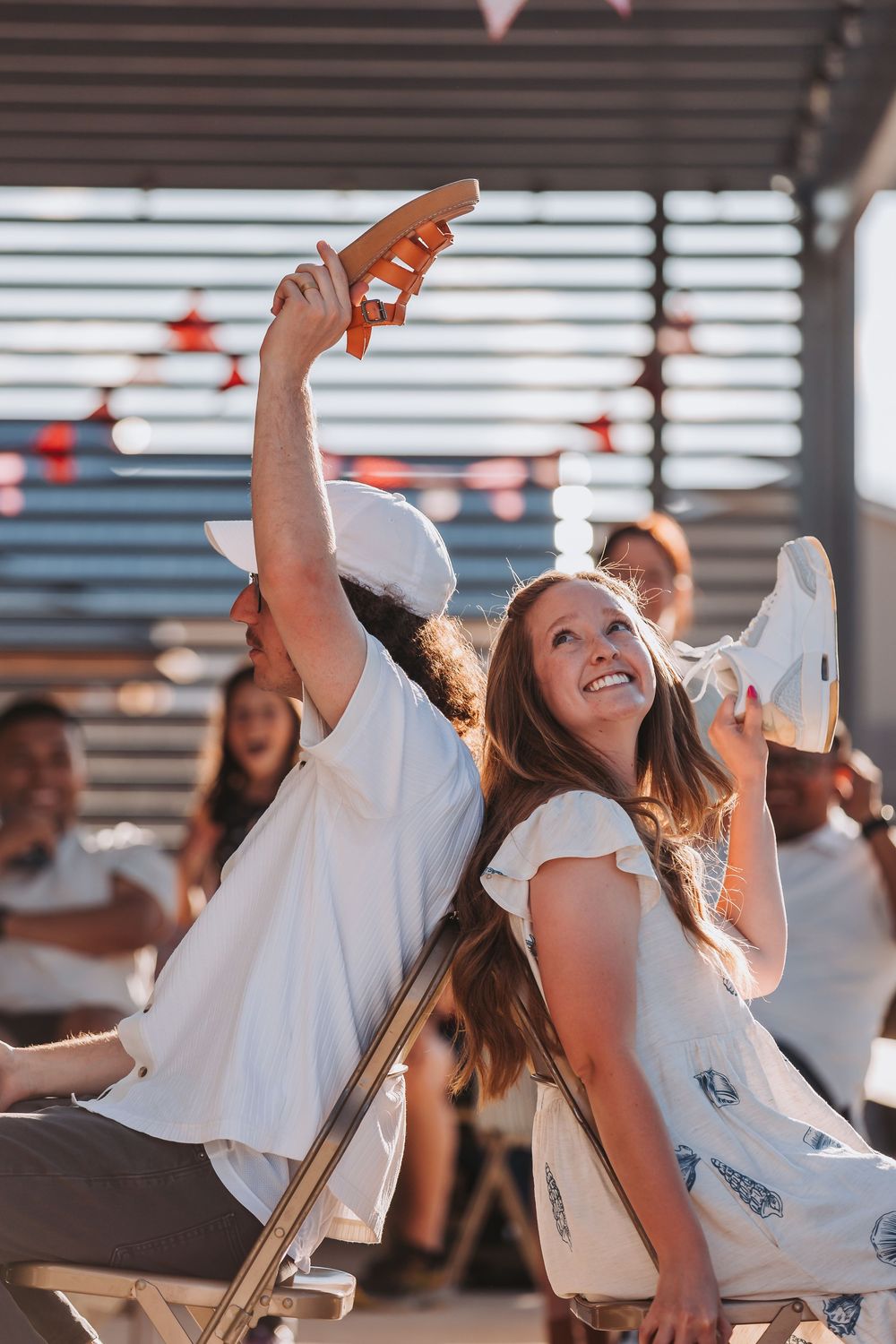 Young people dancing and having fun at a summer party with festive string lights in the background.
