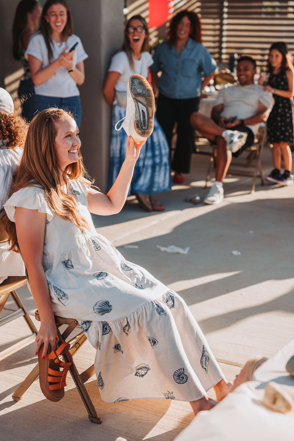 Dancing in flowy white dresses at a sunlit outdoor celebration.