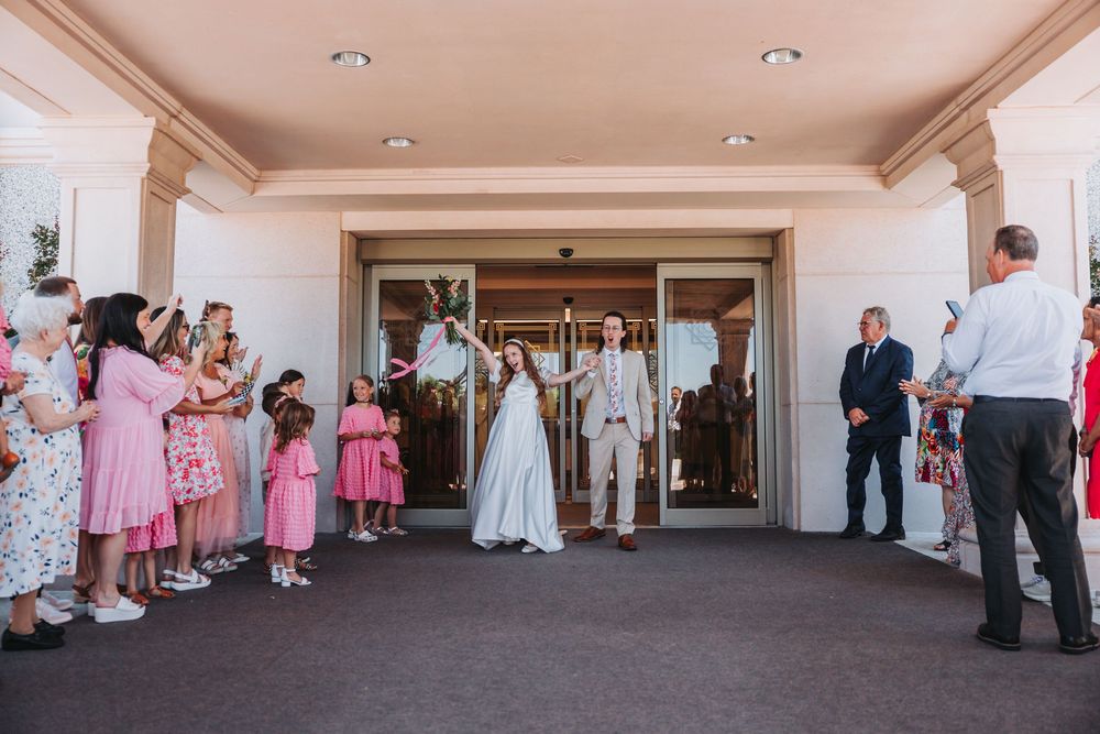 A panoramic view of wedding guests in pink dresses mingling in an elegant white reception hallway.