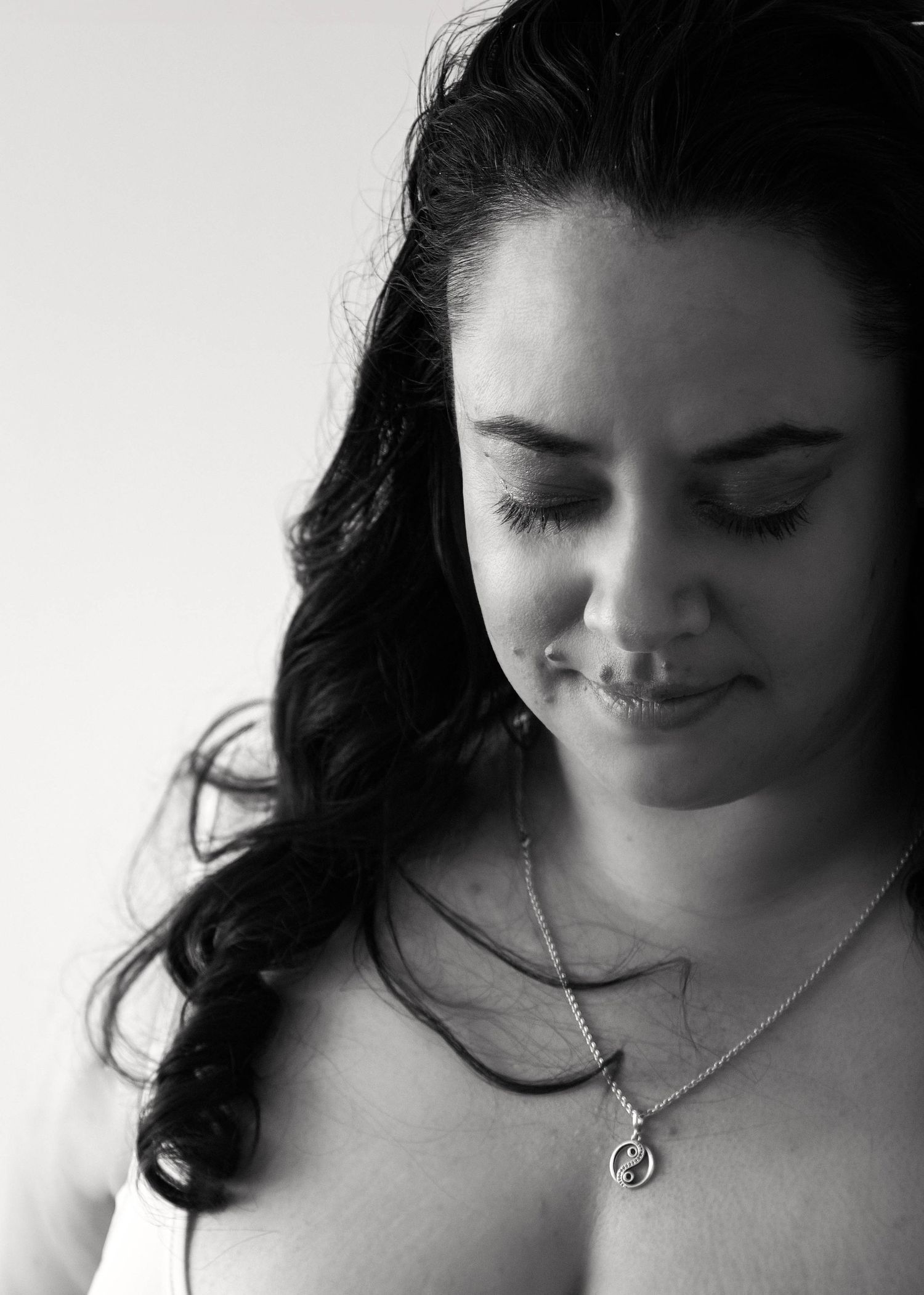 A black and white photo series showing a figure with dark hair and jewelry looking down in different poses.