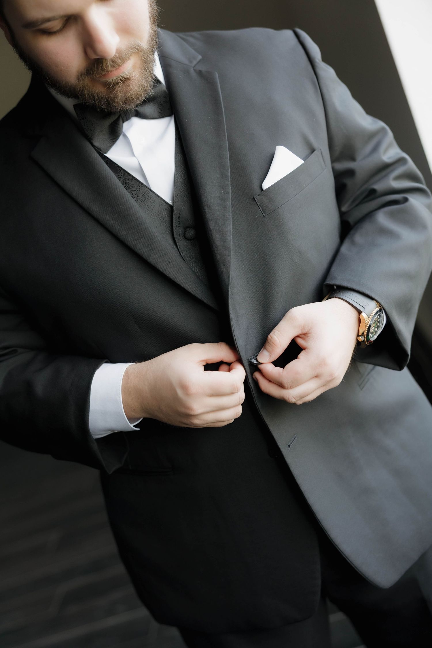 Close-up shots of a groom adjusting his suit jacket buttons before the ceremony.