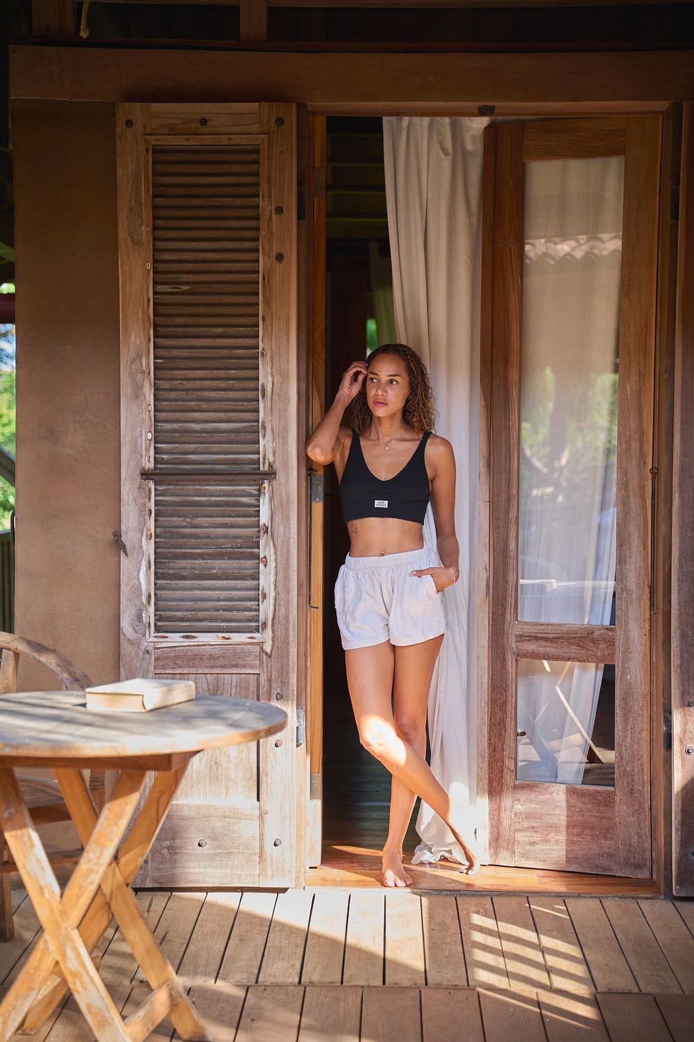 A casual summer look on a rustic cabin porch with wooden shutters and a folding table.