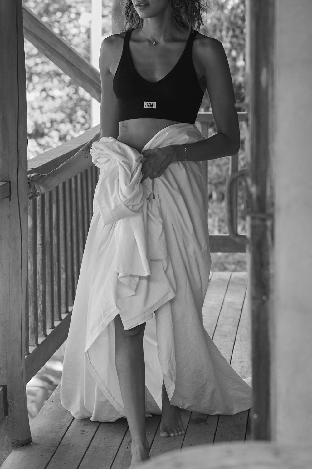 Three black and white photos showcase elegant dresses with black tops and flowing white skirts on a wooden porch.
