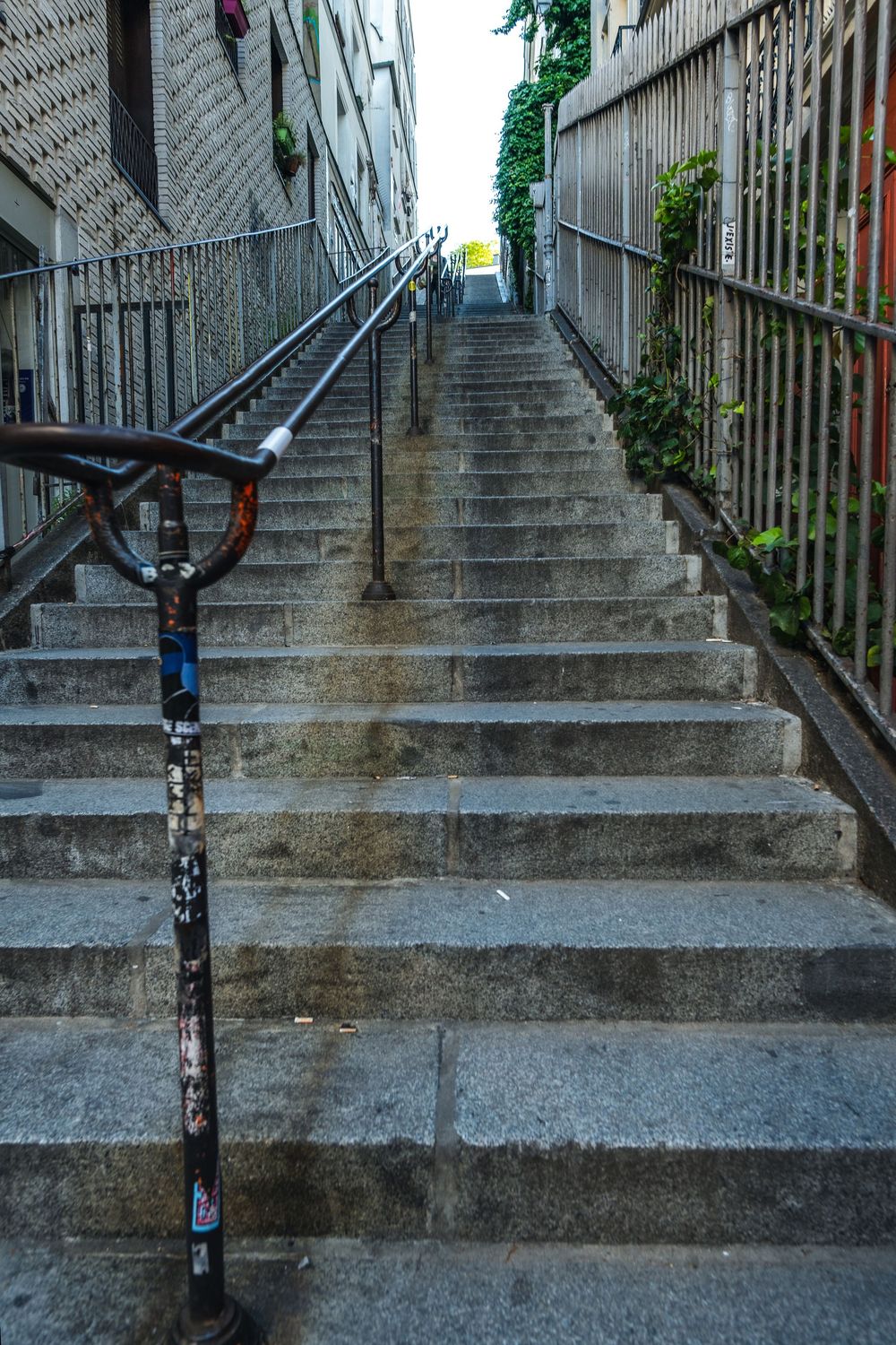 A steep concrete staircase with metal handrails leads upward between buildings.