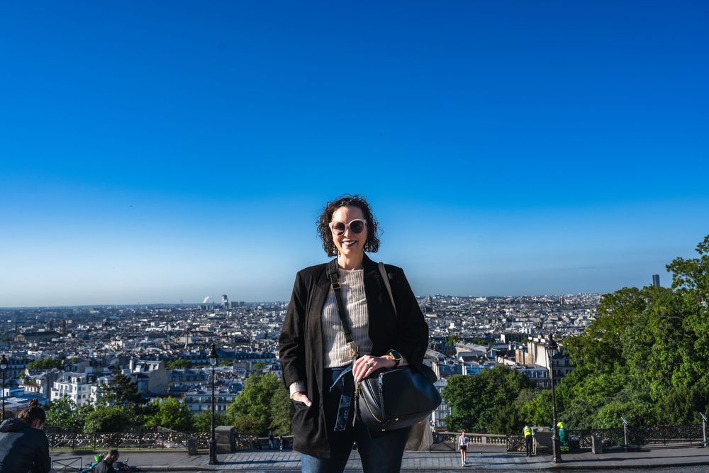 A panoramic view from Montmartre with the Paris cityscape and bright blue sky in the background.
