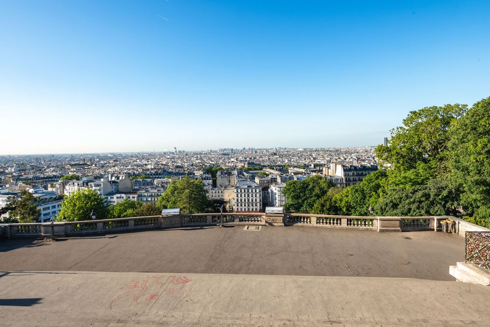 Scenic viewpoint overlooking the Parisian cityscape from Montmartre heights on a clear sunny day.