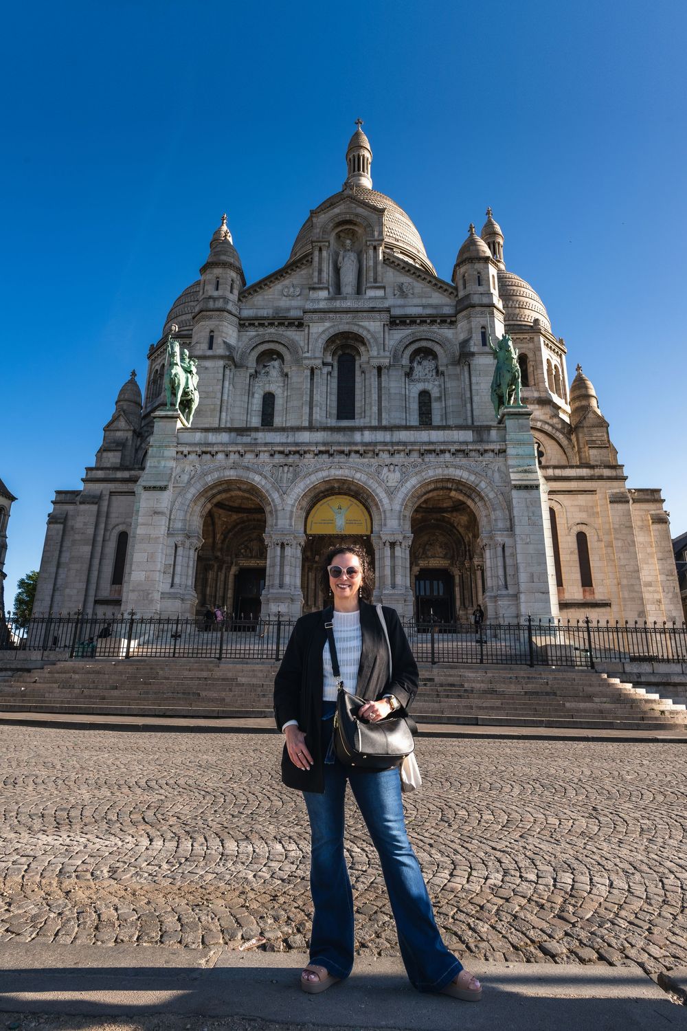 Iconic Sacré-Cœur Basilica in Paris with its white stone facade and multiple domes against bright blue sky.