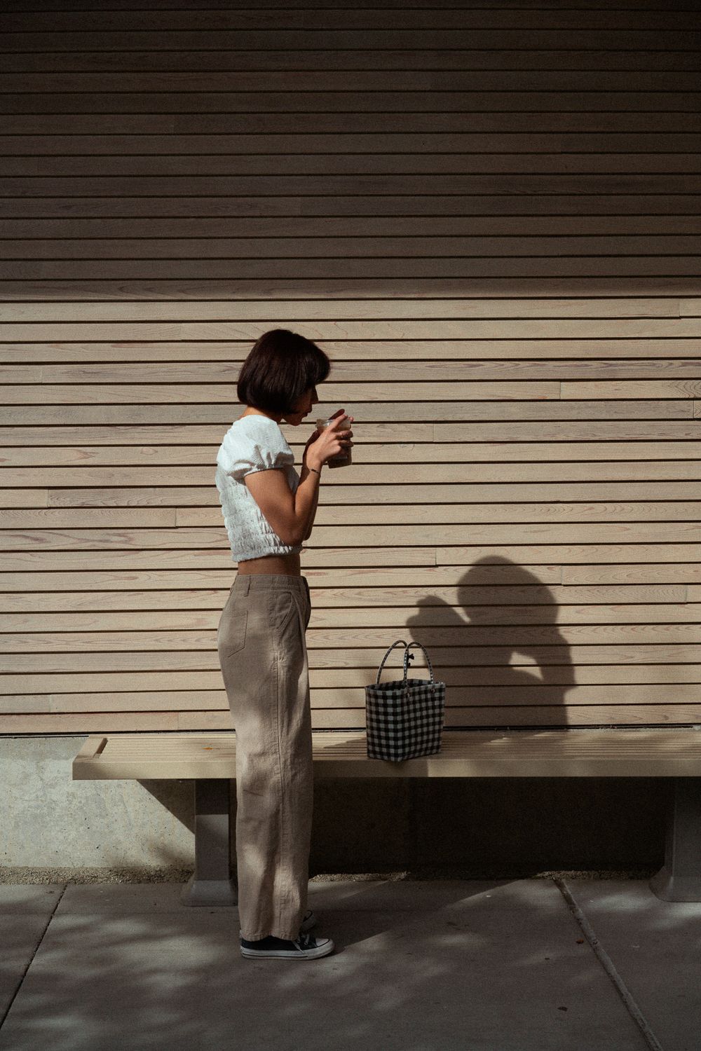 A person in a long skirt stands against a beige wall casting a dramatic shadow in a sequence of four similar images.