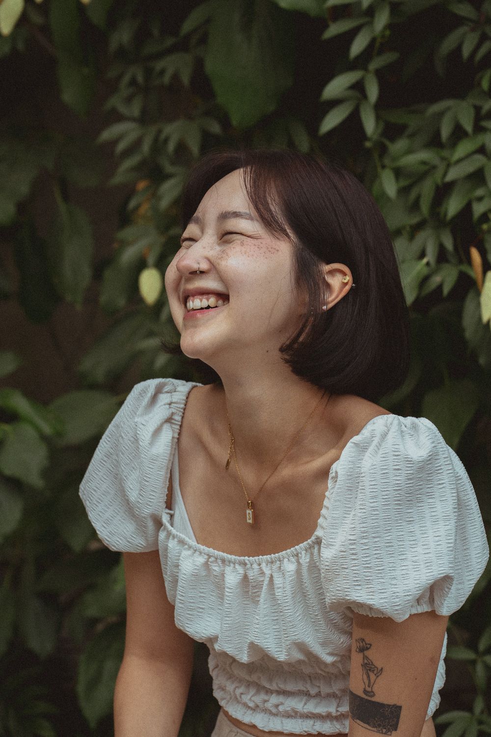 Joy and laughter captured in a series of white dress portraits against lush green foliage background.