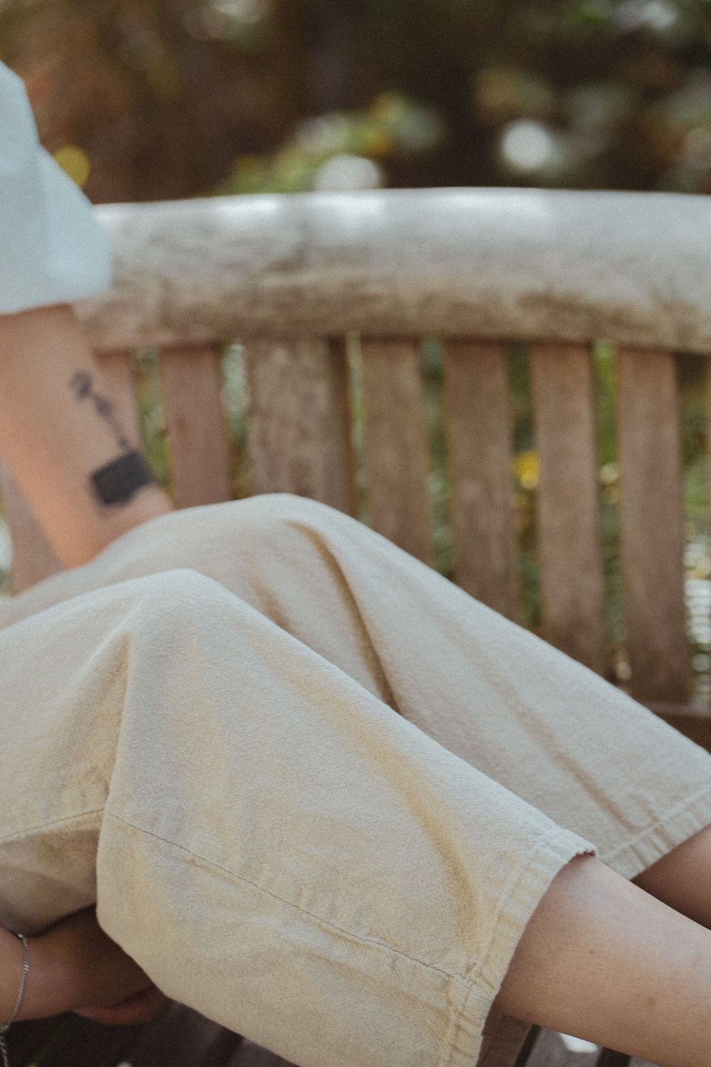 Close-up view of worn beige fabric shorts showing textured details and distressed edges against a rustic wooden fence.