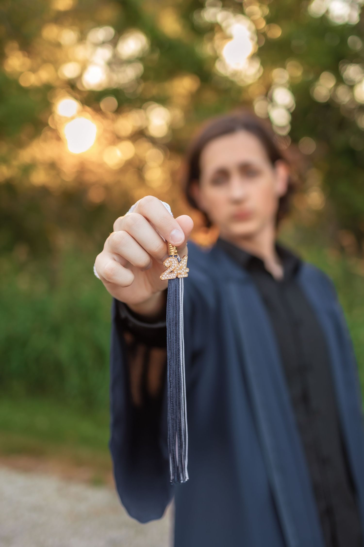 A hand holds up a glass test tube against a blurred golden sunset background with greenery. Novi Michigan Senior Photographer