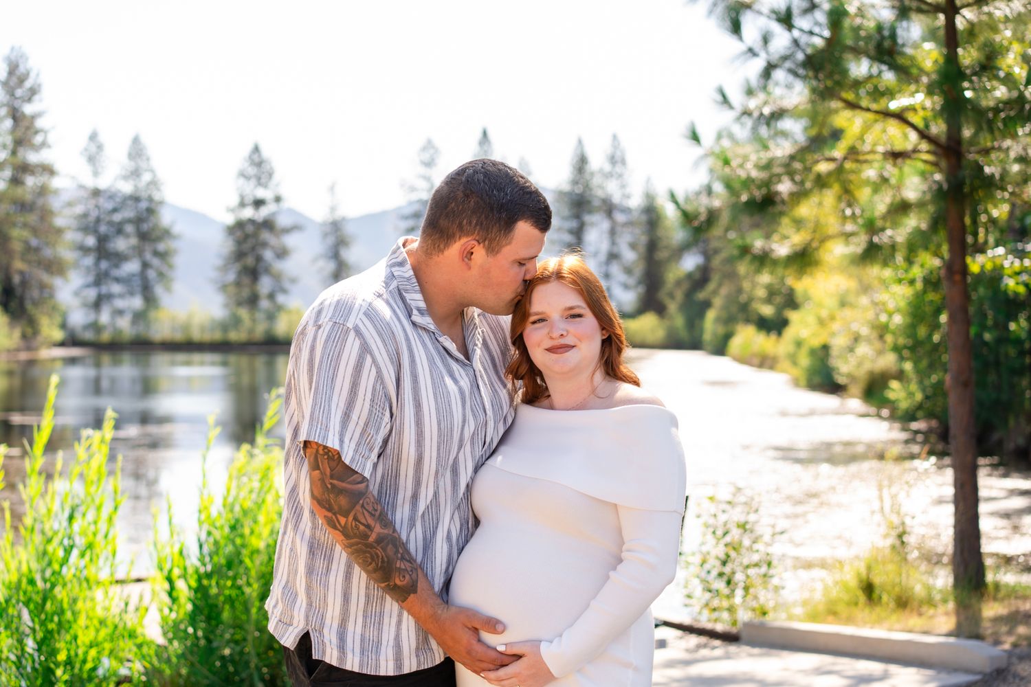 Maternity Portrait of a couple expecting their first baby at Pacifica Gardens in Williams, Oregon with the pond and mountains behind them