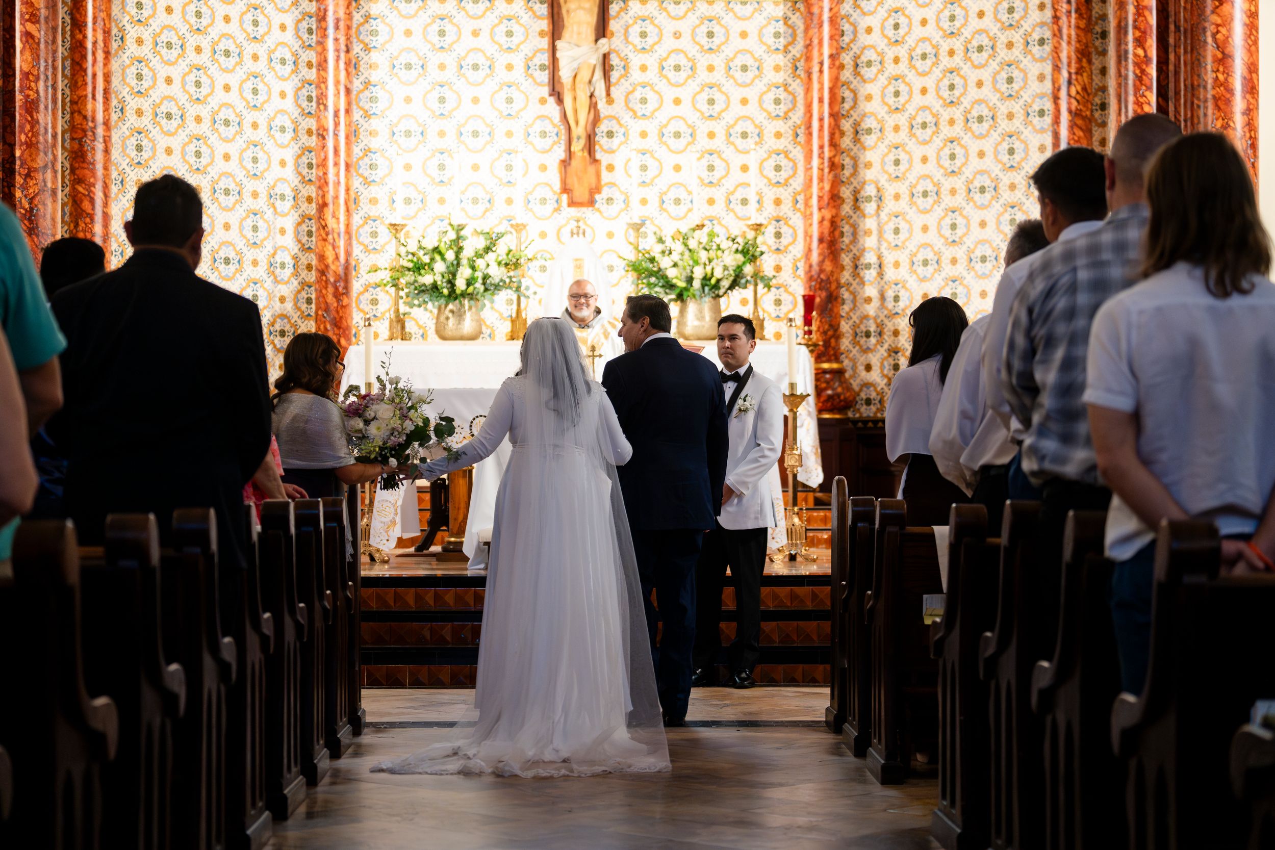 Interior view of a church during a wedding ceremony with guests seated in wooden pews.