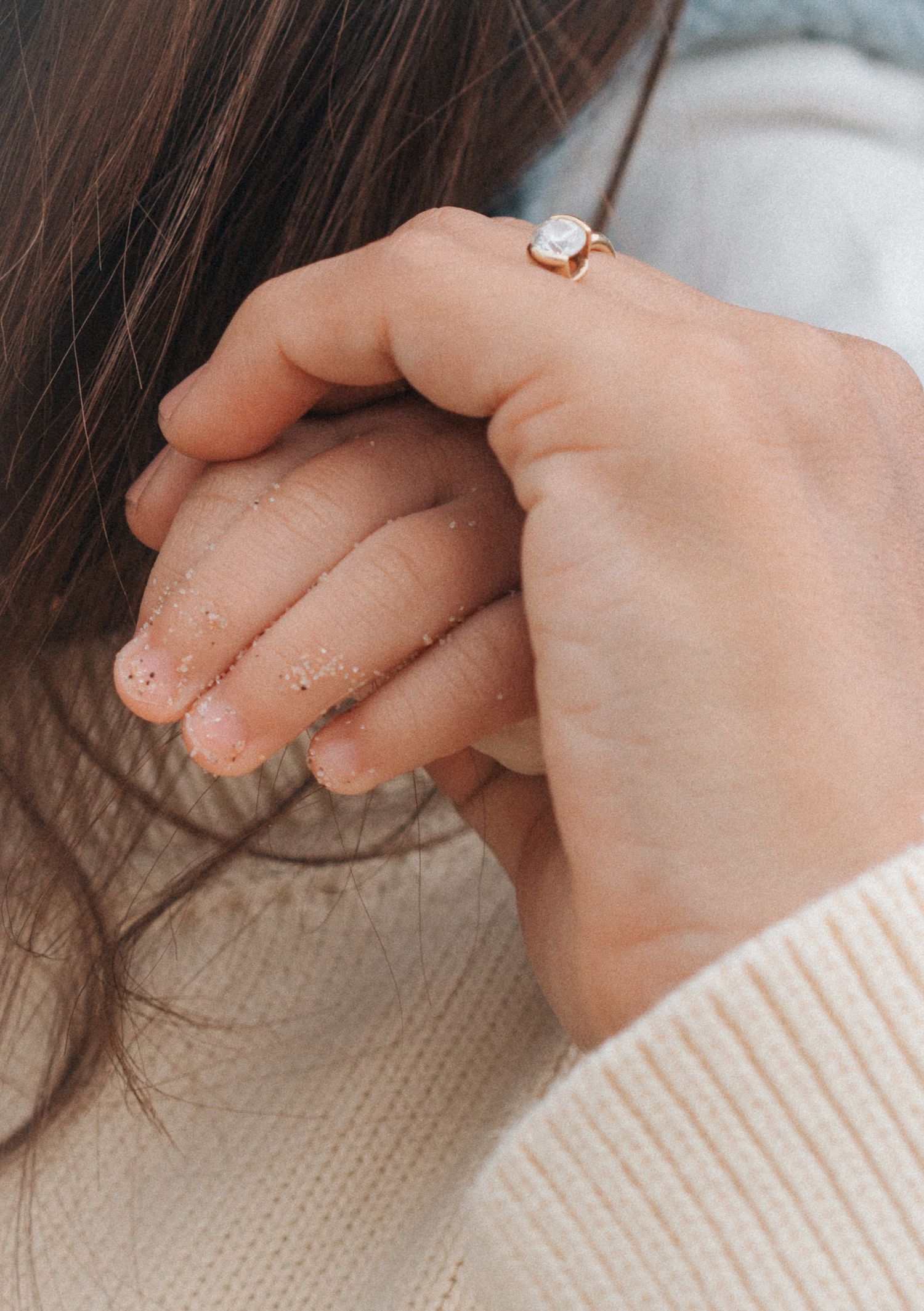 Close-up shots showing fingers gently playing with soft brown hair strands against a beige knit sweater background.