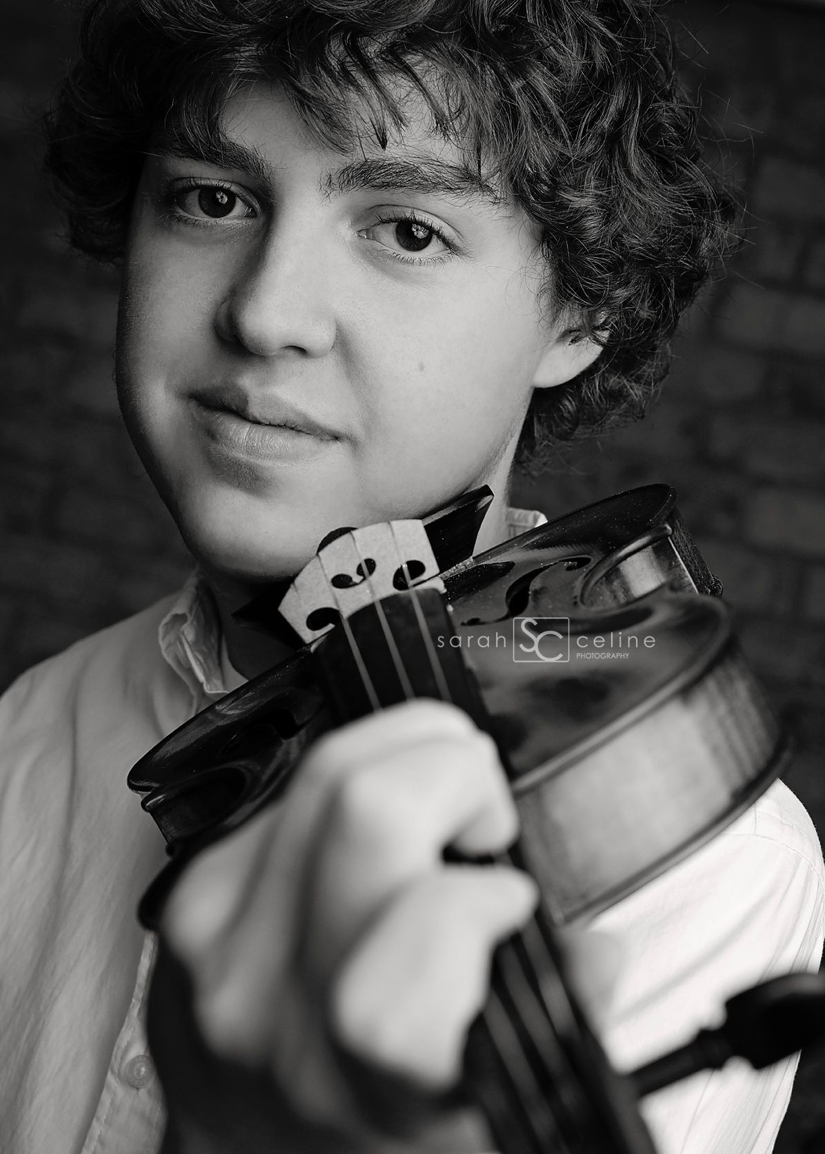Black and white portrait of a musician posing with a violin against a dark background.