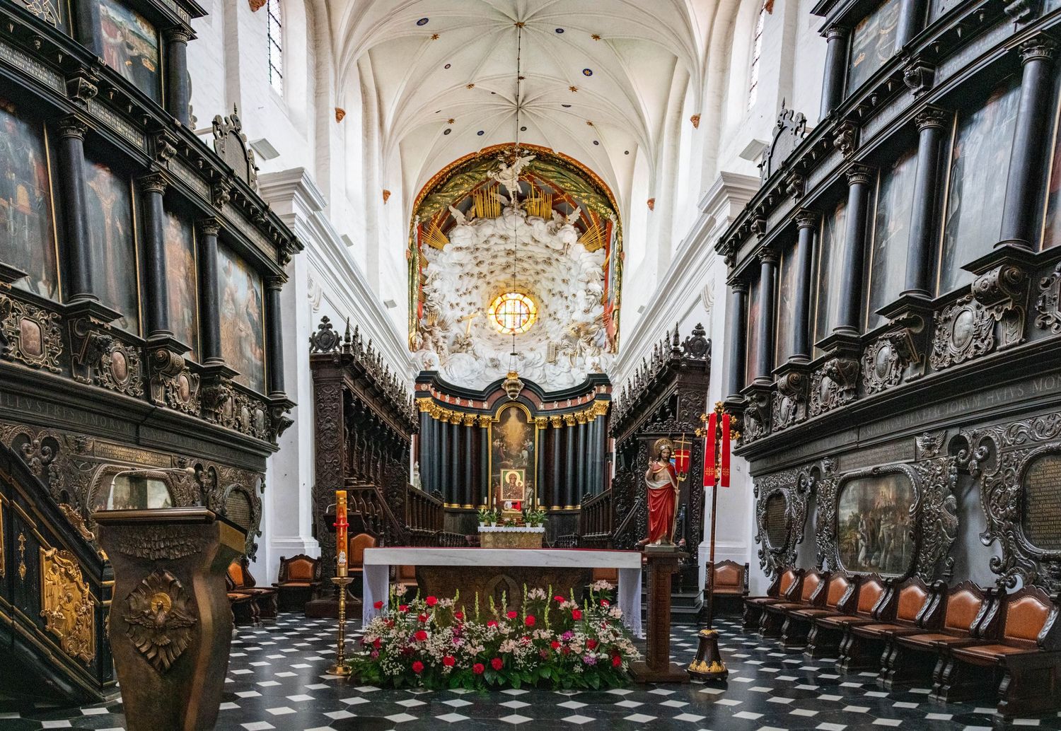 Gothic church interior with vaulted ceiling, ornate choir stalls, and decorative baroque details.