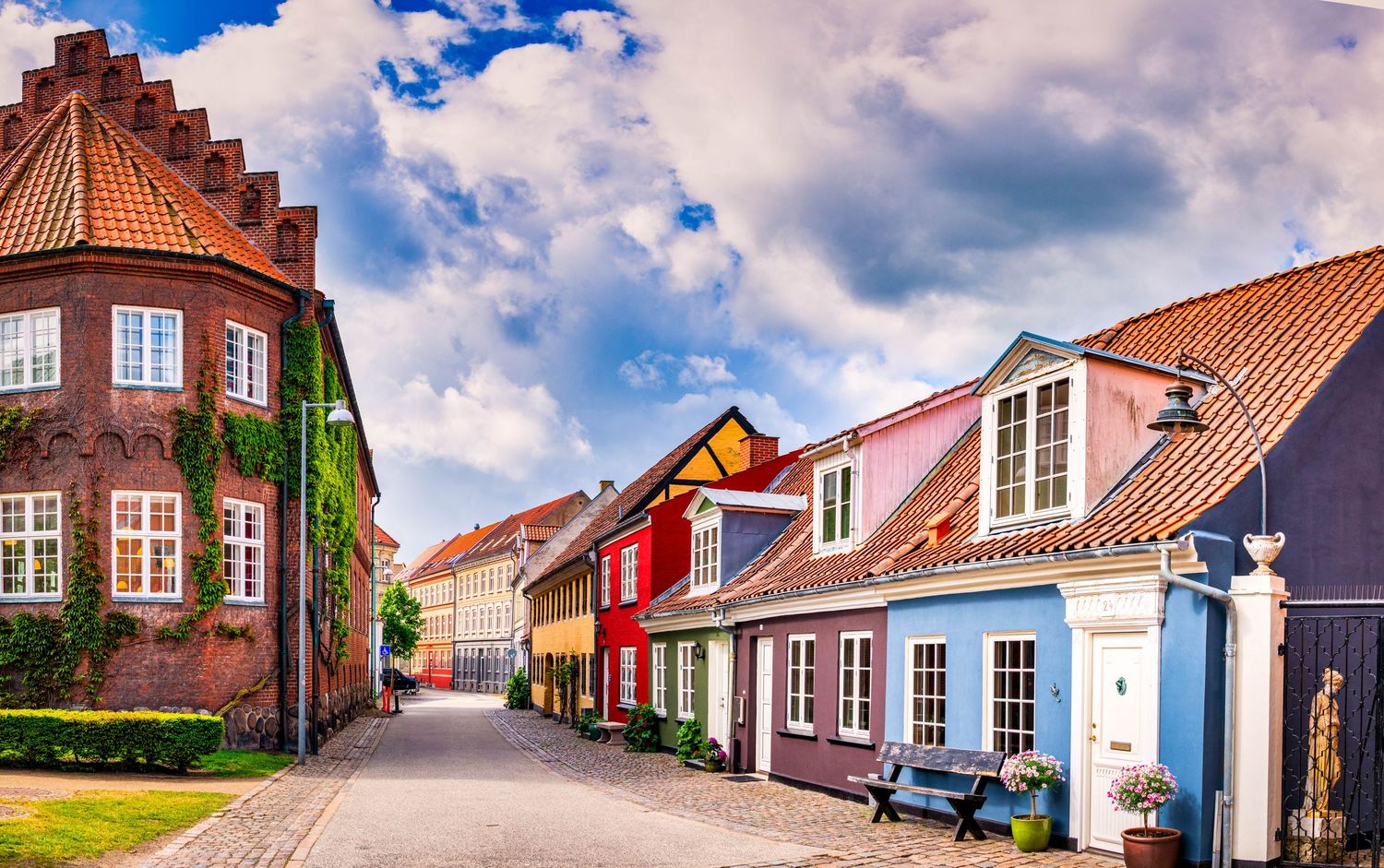 Charming cobblestone street lined with traditional Danish buildings under blue skies.