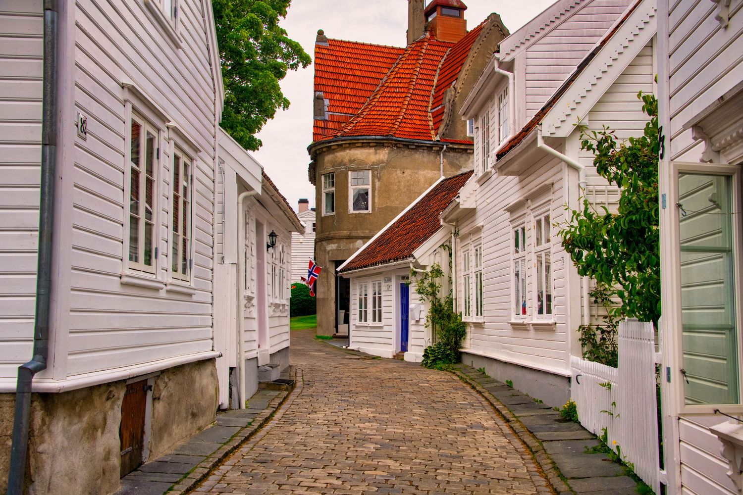 Row of historic white wooden buildings along quiet street in Scandinavian town.