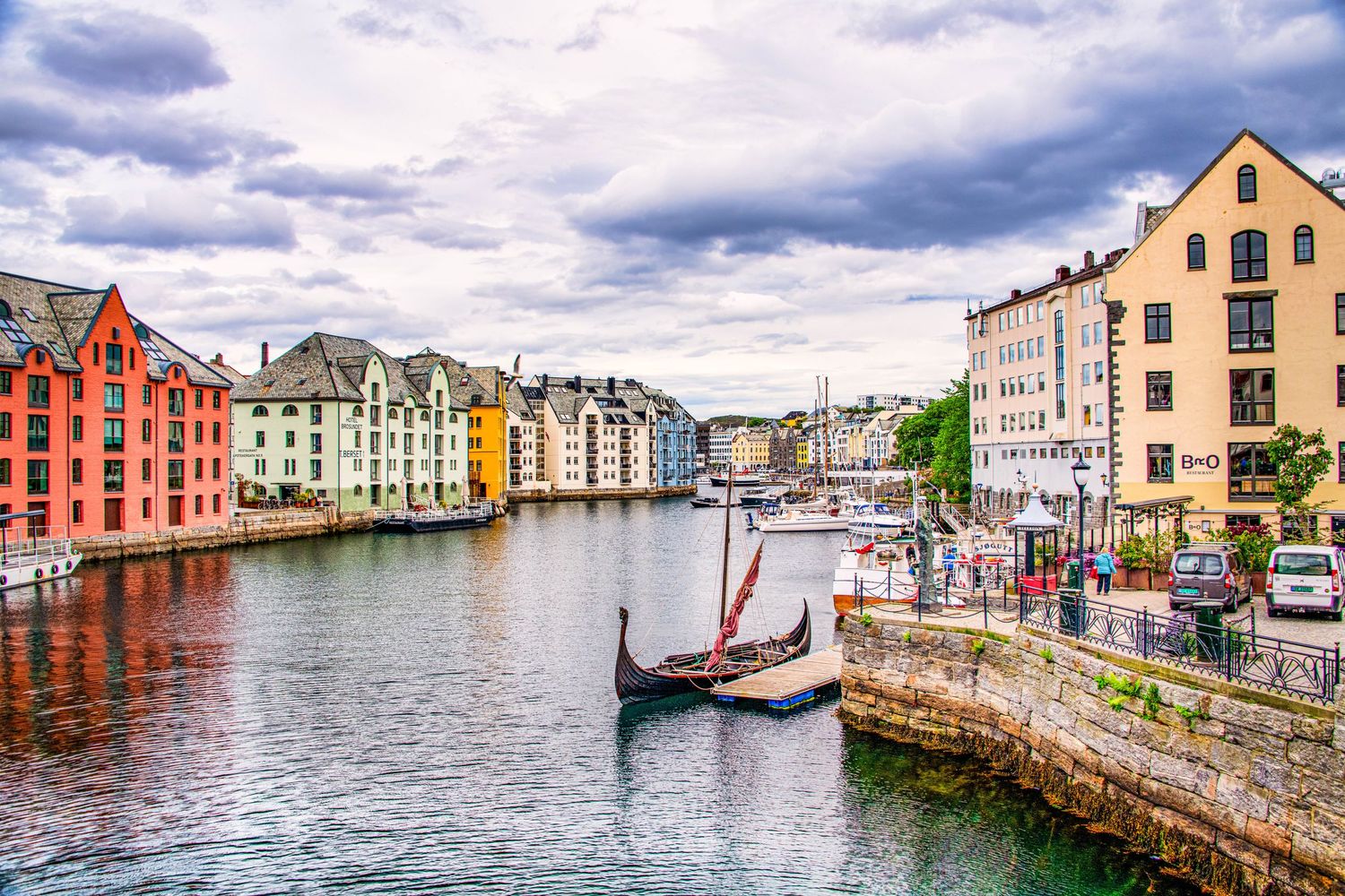 Panoramic view of colorful buildings reflecting in the harbor waters of Alesund, Norway.