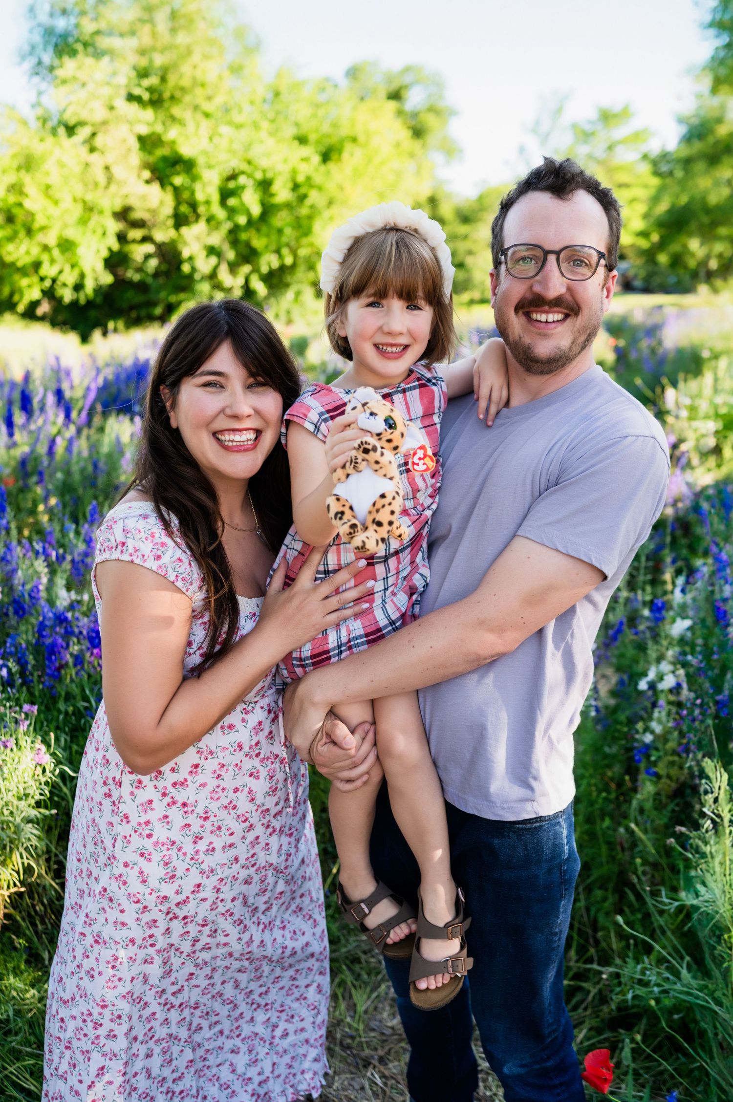 Family of three huddled together during a spring time family mini session in wildflowers