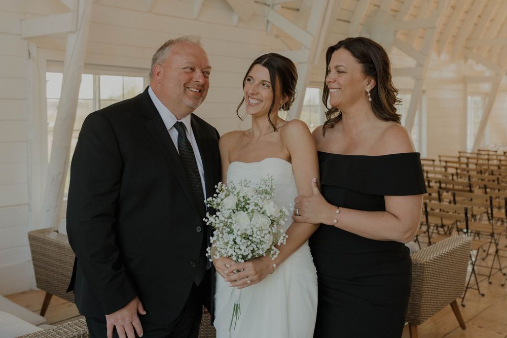 Wedding party members in black and white attire gather for formal photos in an elegant venue.
