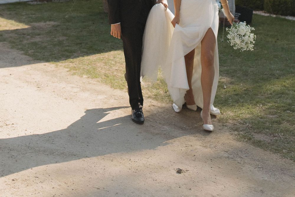 Wedding party members walk together on a gravel path during outdoor photo session.