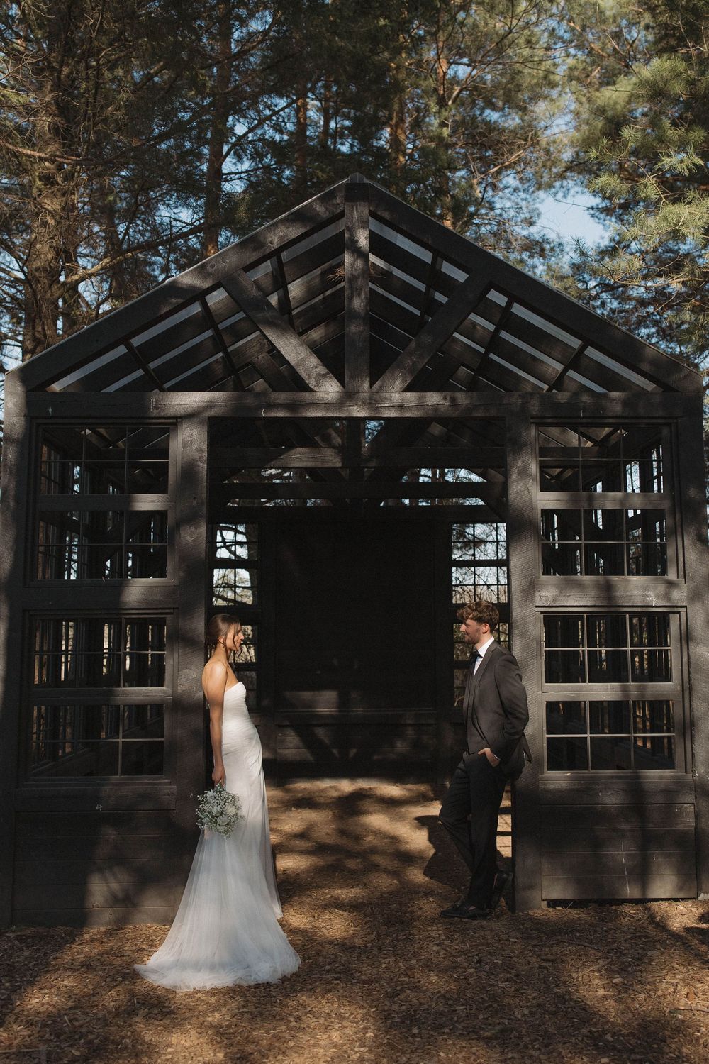 A rustic wooden wedding chapel structure in a pine forest creates a romantic outdoor ceremony setting.