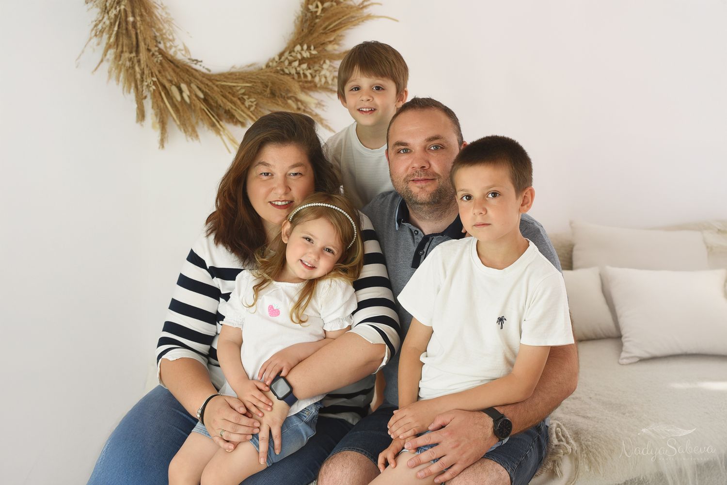 Family portrait outdoors in a garden setting with natural greenery background in autumn.
