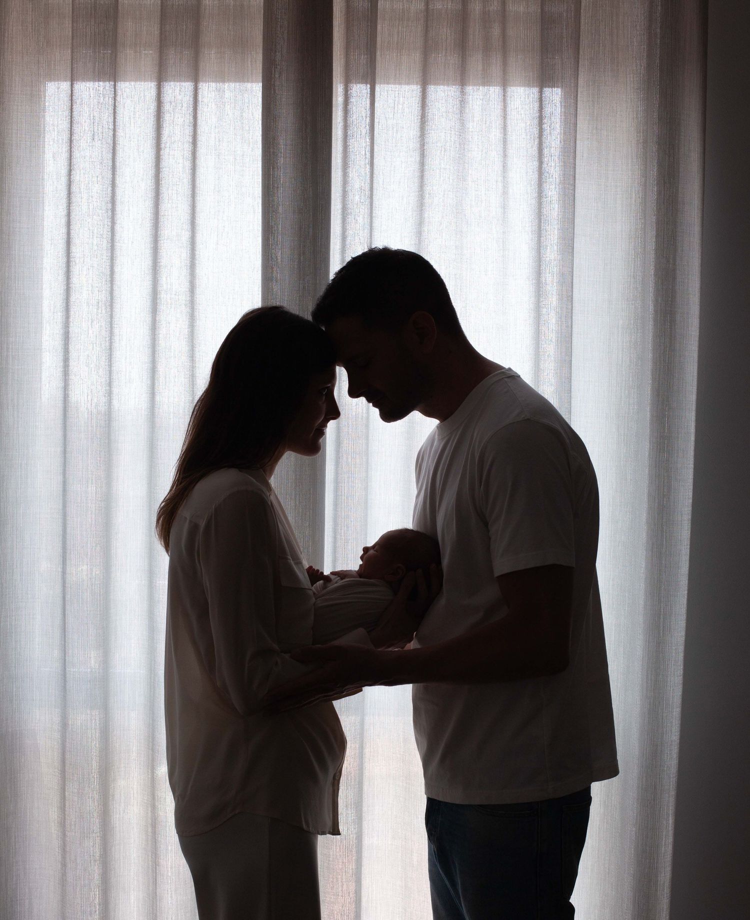 mamma e papà con neonata in controluce