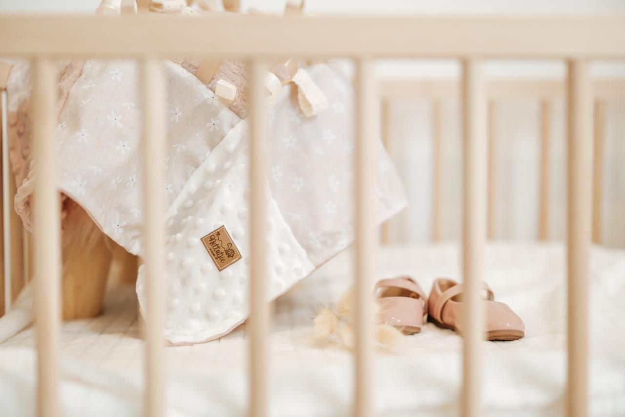 Baby feet in white crib with soft bedding and natural lighting through window.