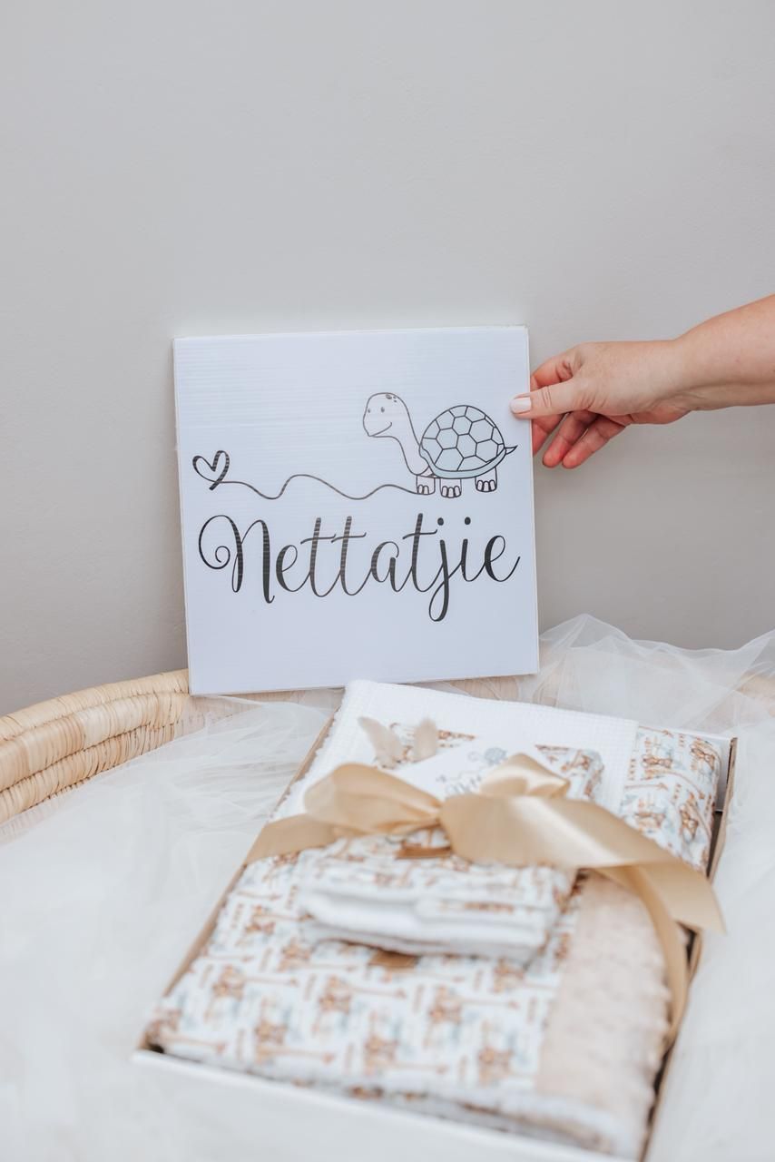 A hand holds a white notecard with calligraphy text against a soft beige background with white packaging materials.